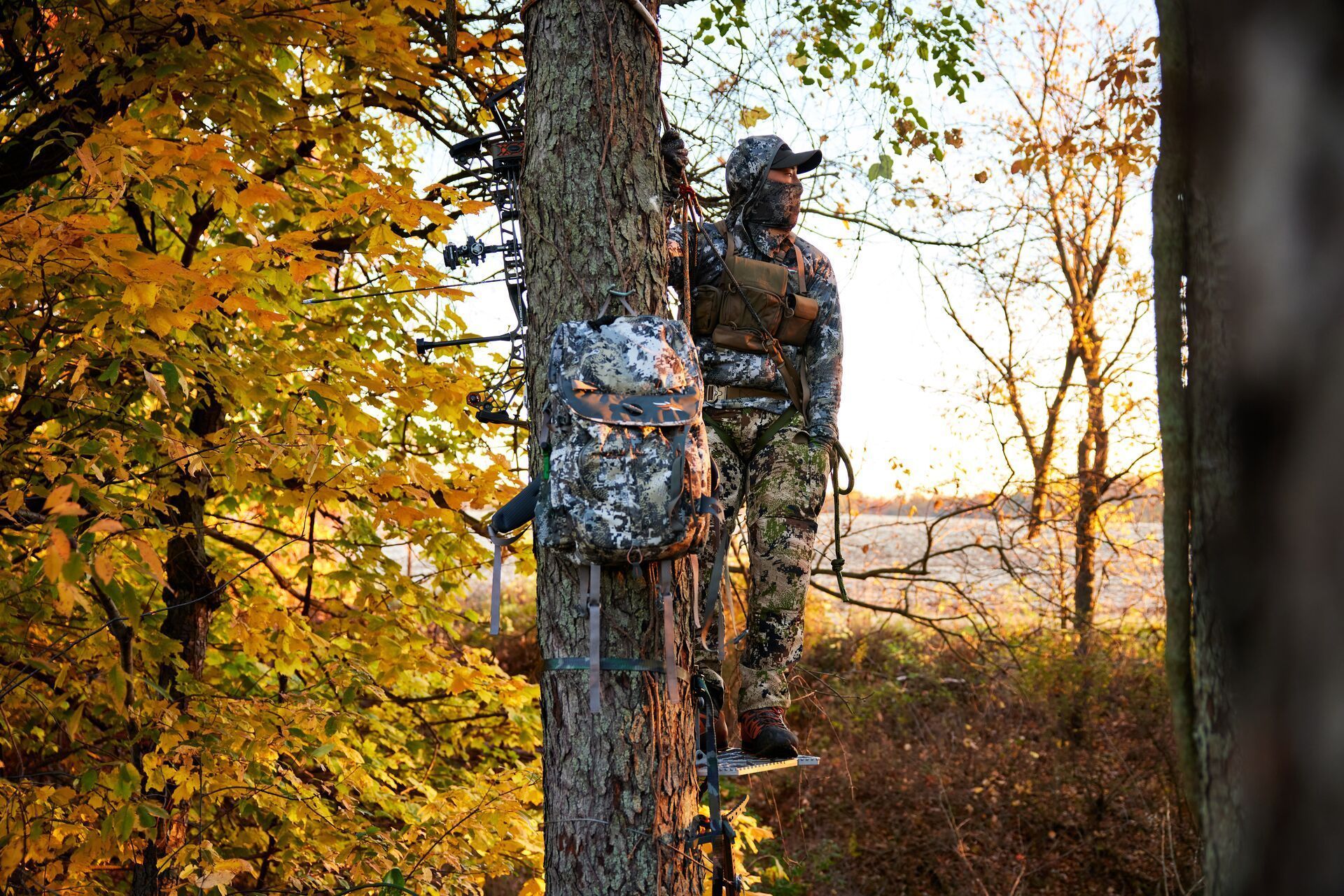 Hunter wears camo while in a tree stand with gear for deer hunting.