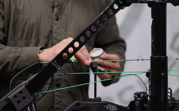 Close-up of John Dudley adding string wax to a bowstring, maintenance for compound bows concept.