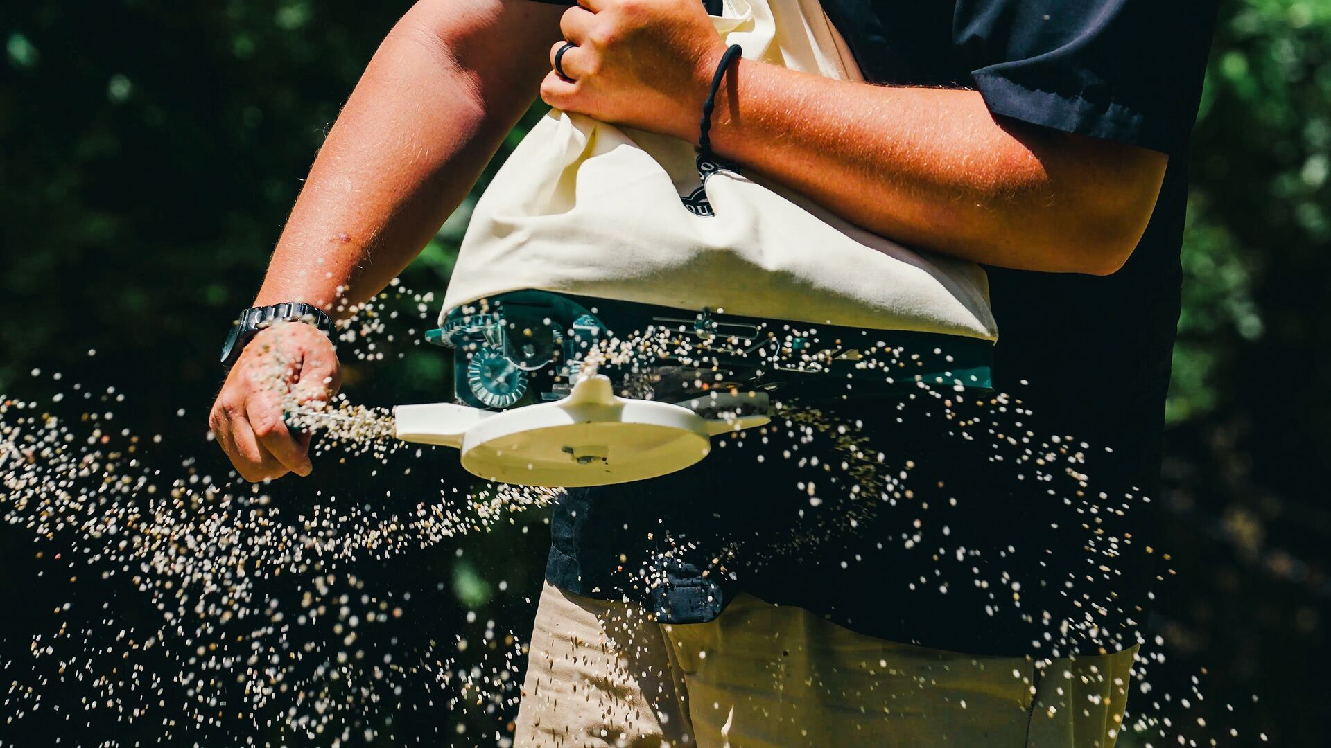 Close-up of someone using a seed spreader, deer food plot seed concept.