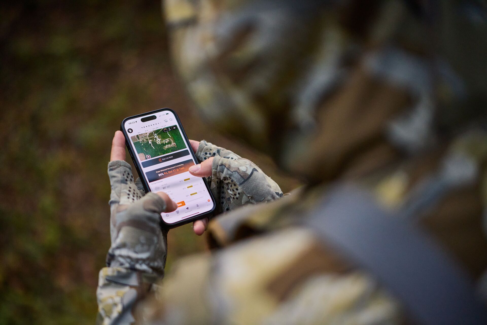 Over shoulder view of hunter using HuntWise hunting app on phone.
