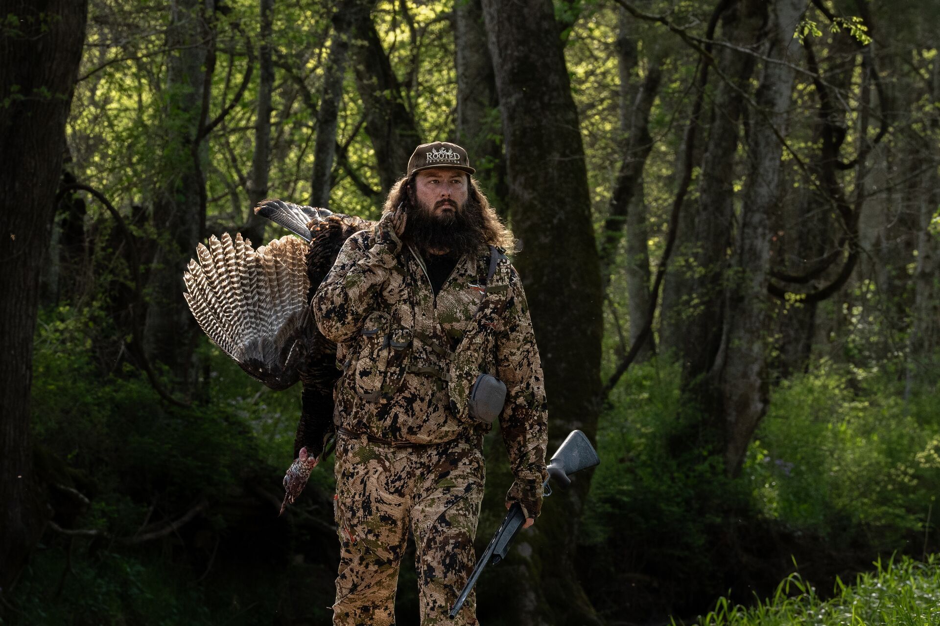 Ben Cole of RootedTV carries a turkey after a hunt, spring hunting concept.