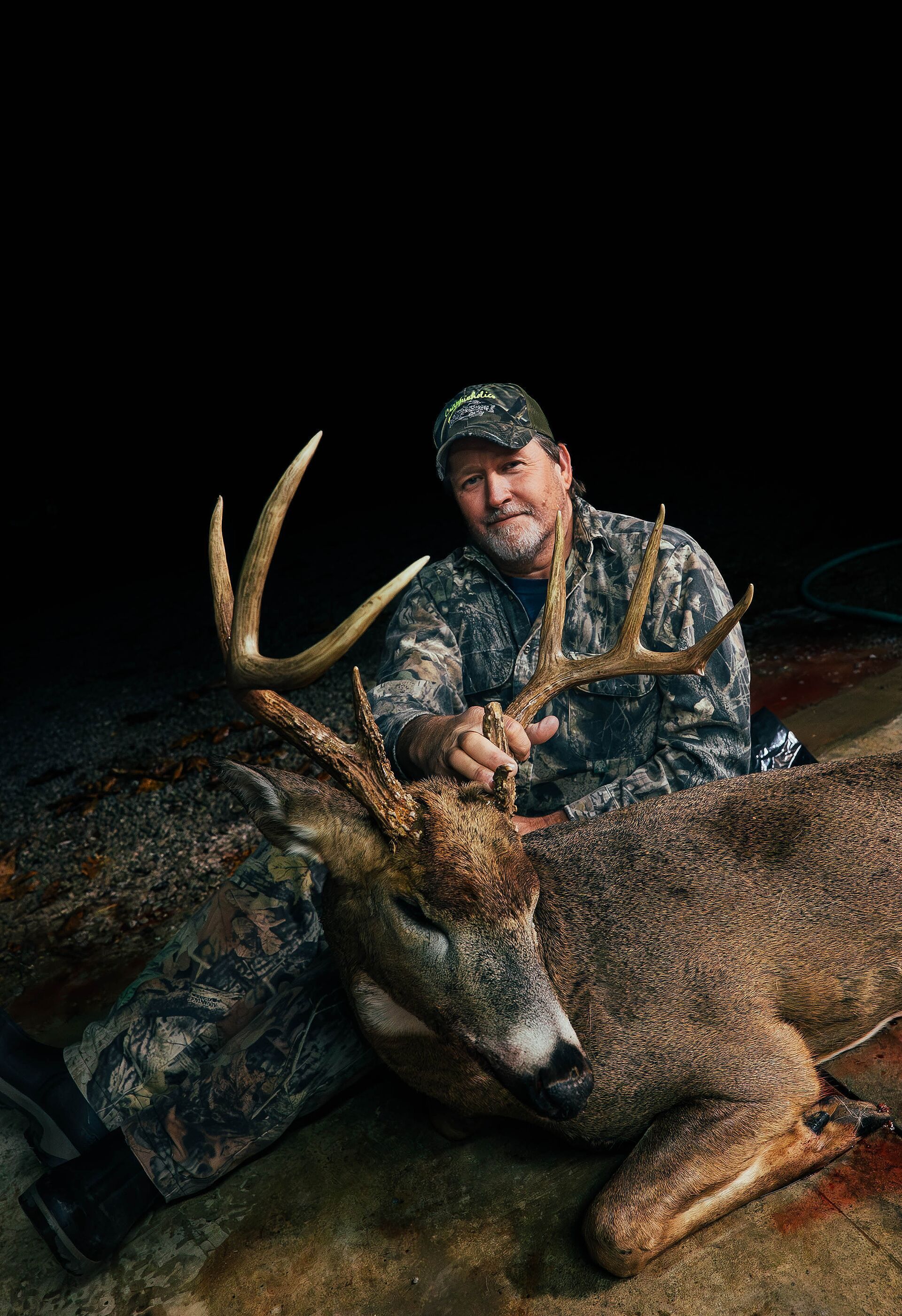 Hunter shows buck deer on ground after hunt in the evening.