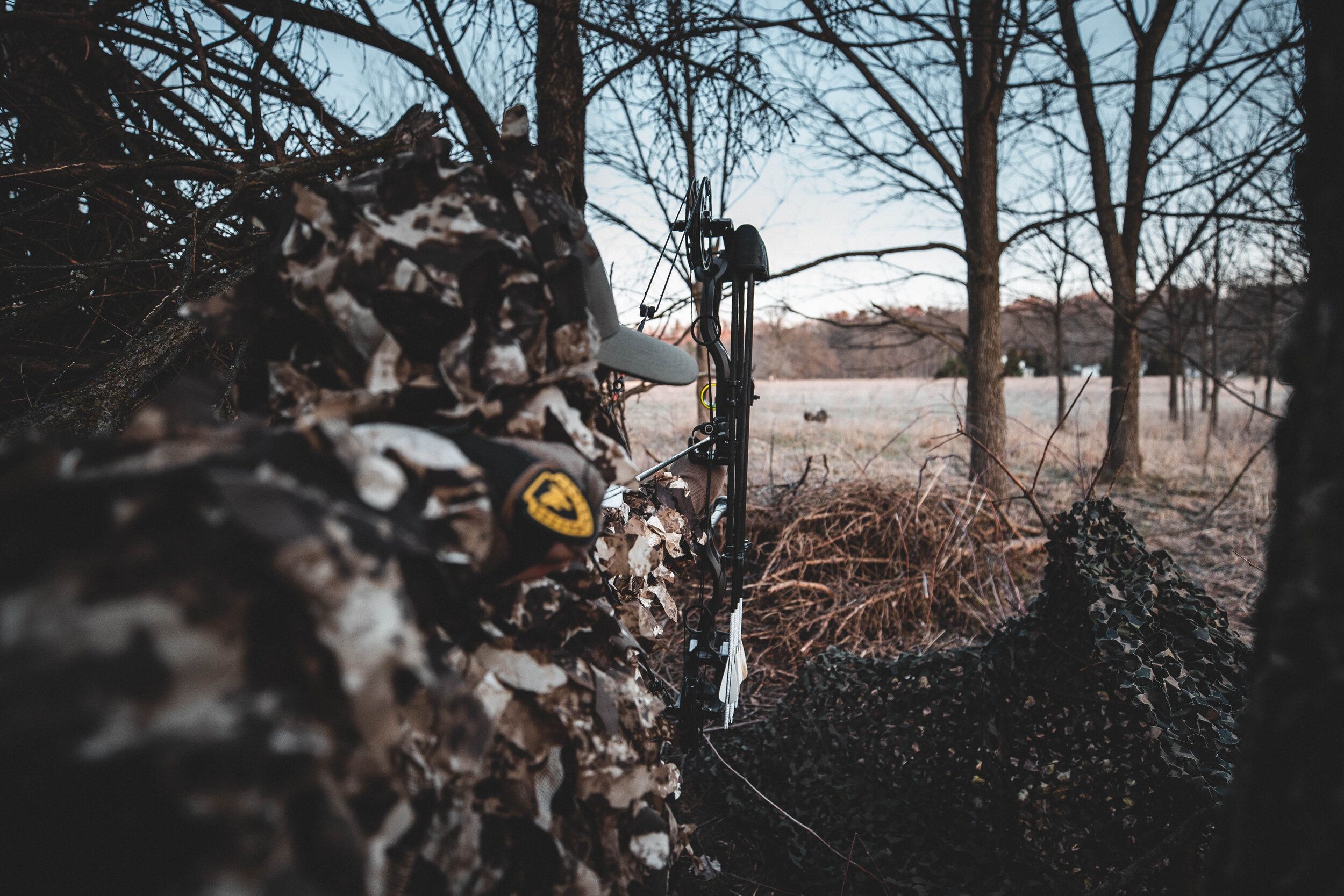 A hunter drawing a bow in the woods, protect your bow with a bow case concept.