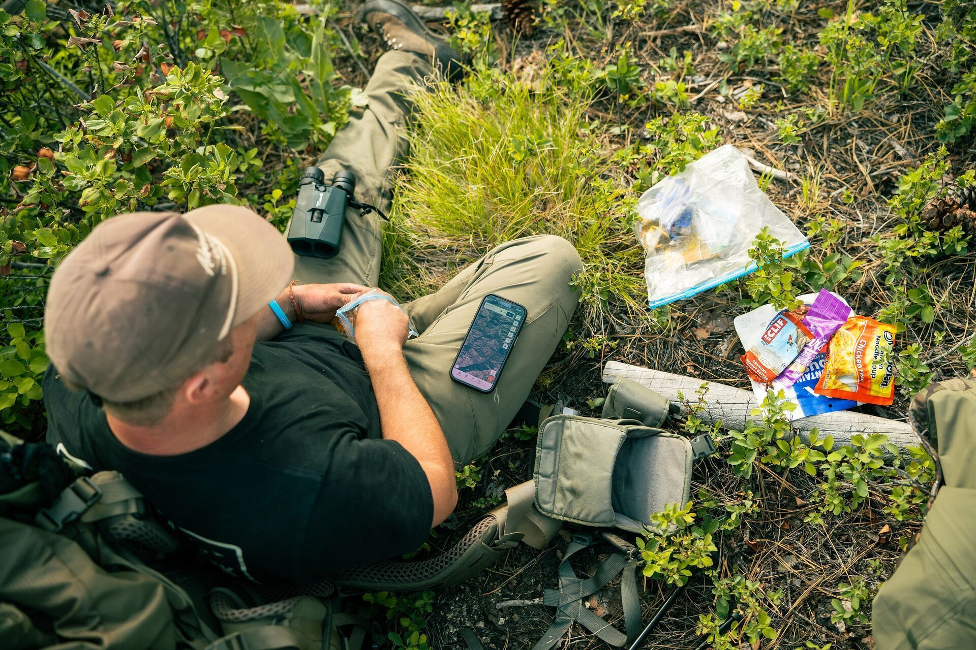Hunter on the ground with gear and HuntWise on phone., elkl hunt planning concept.