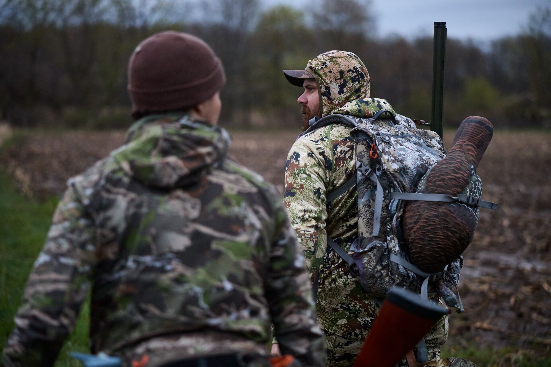 Two hunters walk with turkey hunting gear and decoy, Georgia turkey hunting concept.