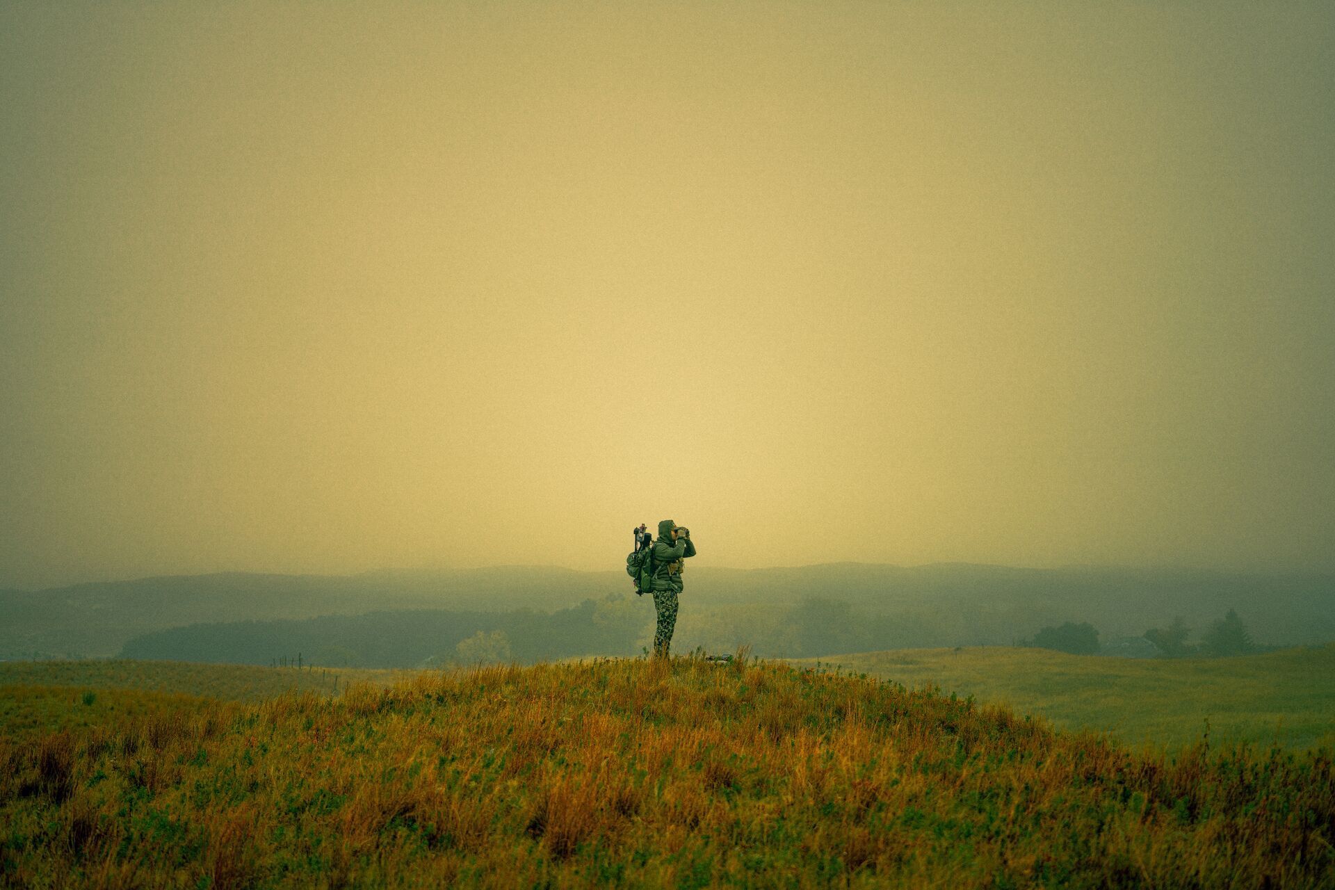 Hunter using binoculars on a hill, ethics in hunting concept.