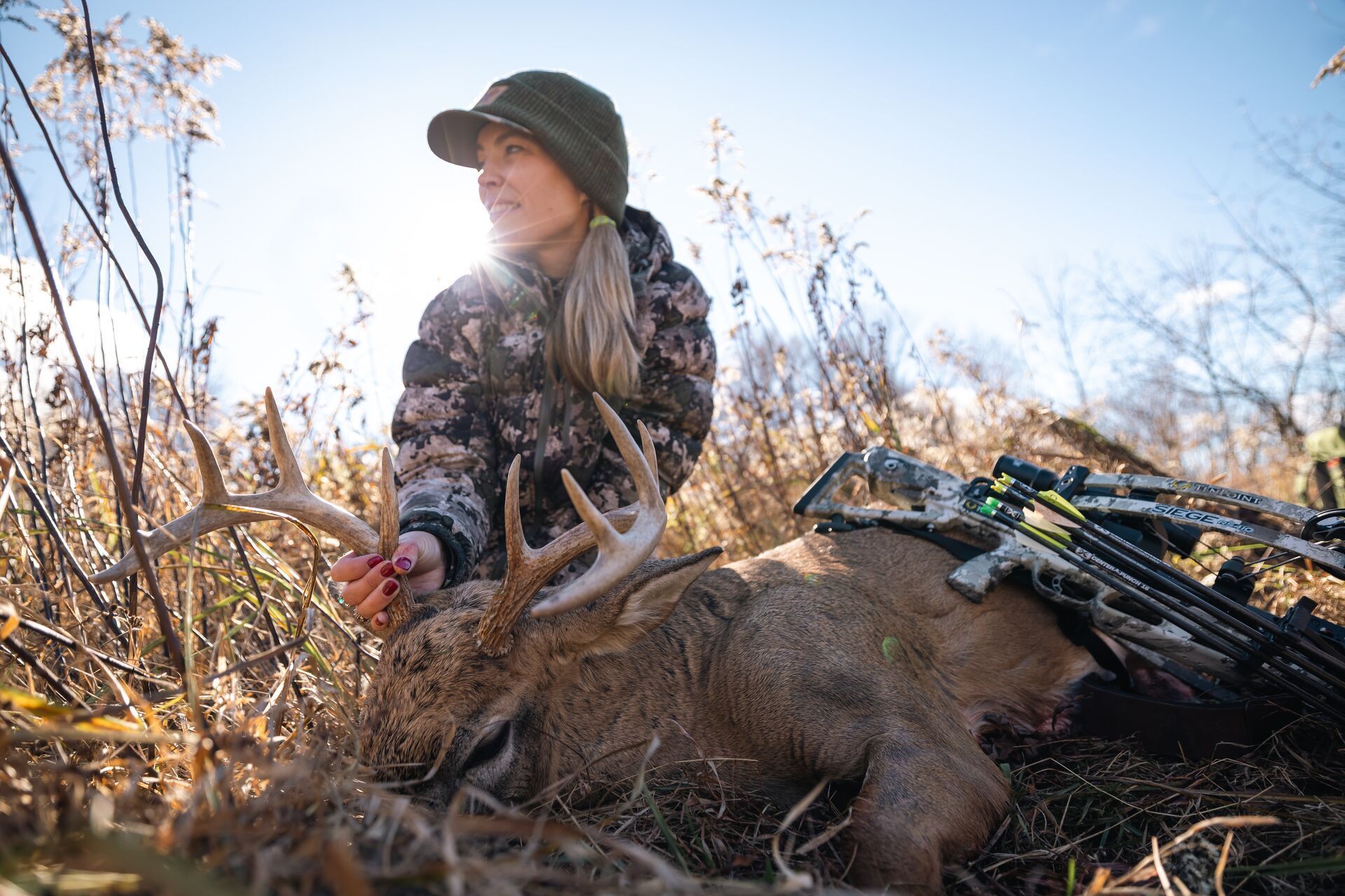 A female hunter shows off a whitetail buck after a hunt, Iowa hunting seasons concept.