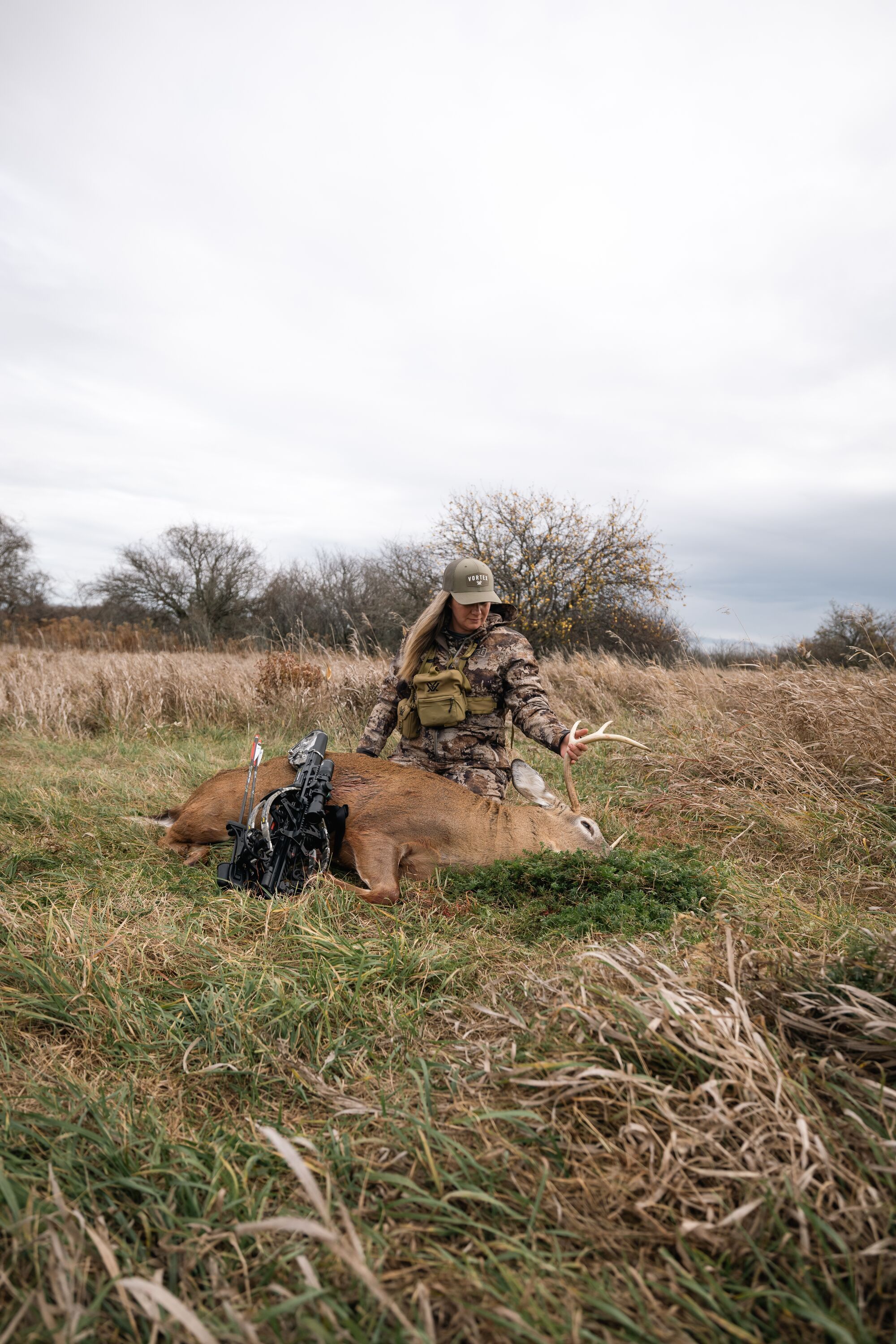 A female hunter looks down at a downed buck deer after a hunt, cooking wild venison concept.