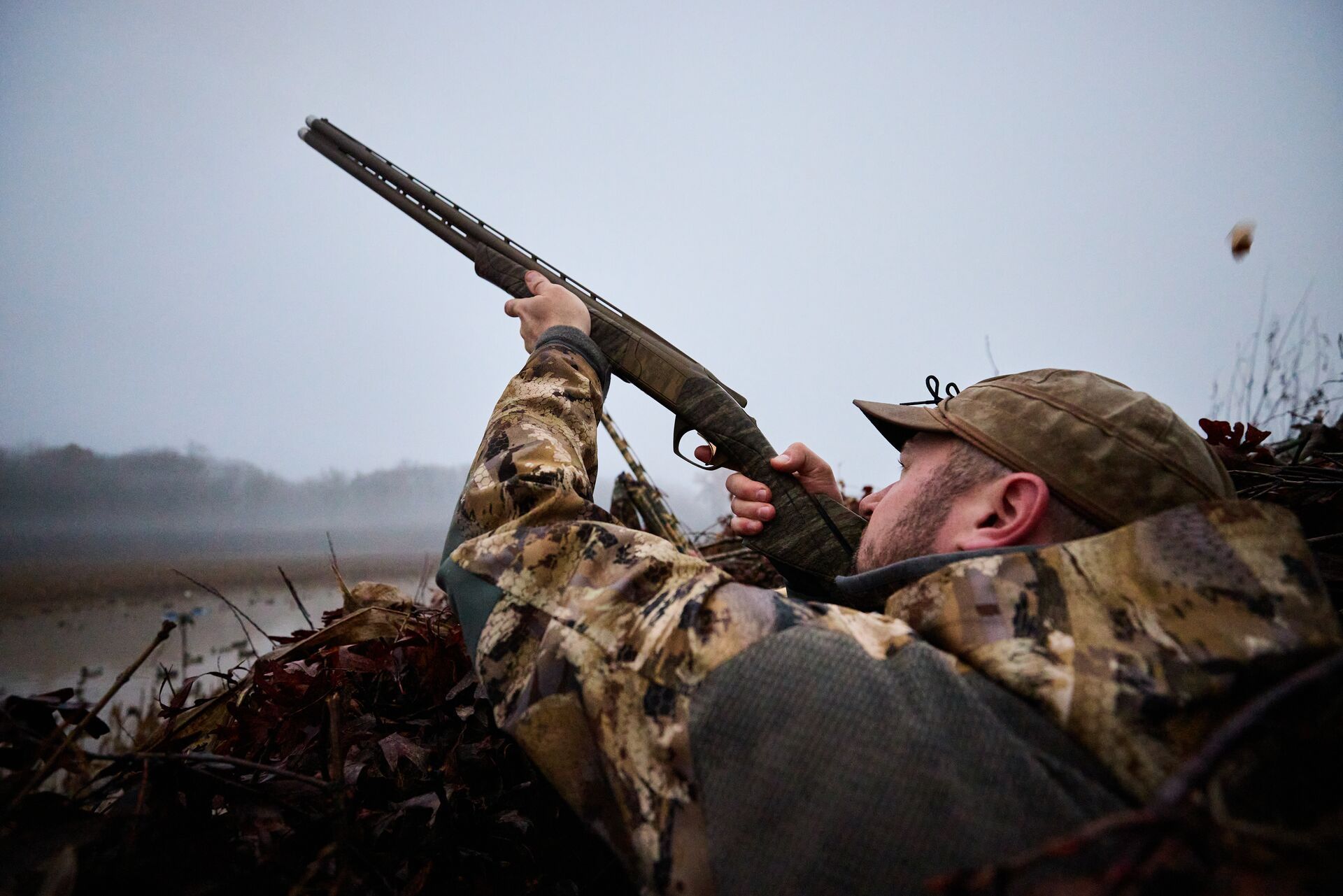 A hunter aims a shotgun while waterfowl hunting, rules of fair chase concept.