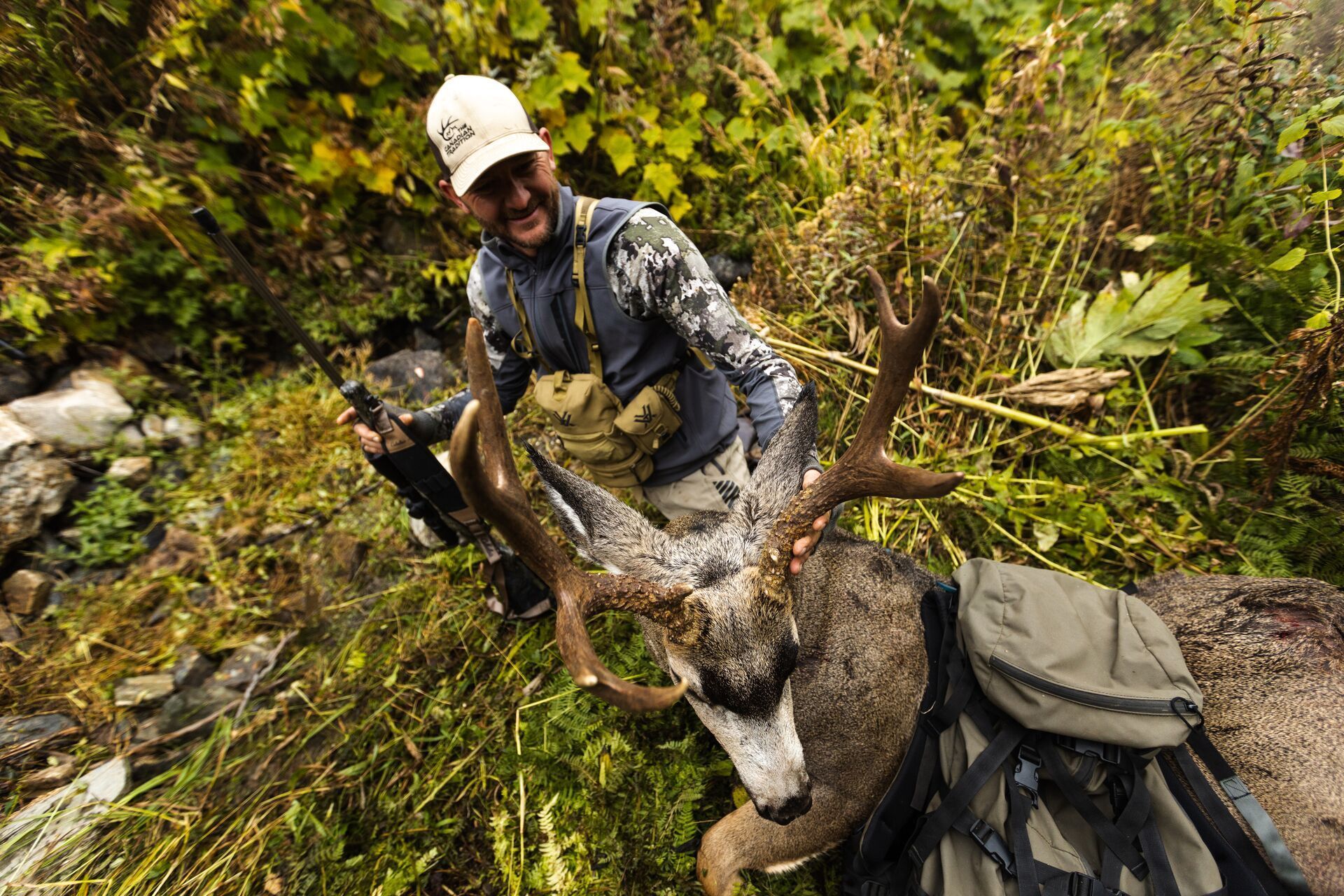 Hunter smiling with rifle and buck deer after a hunt, field dress a deer concept.