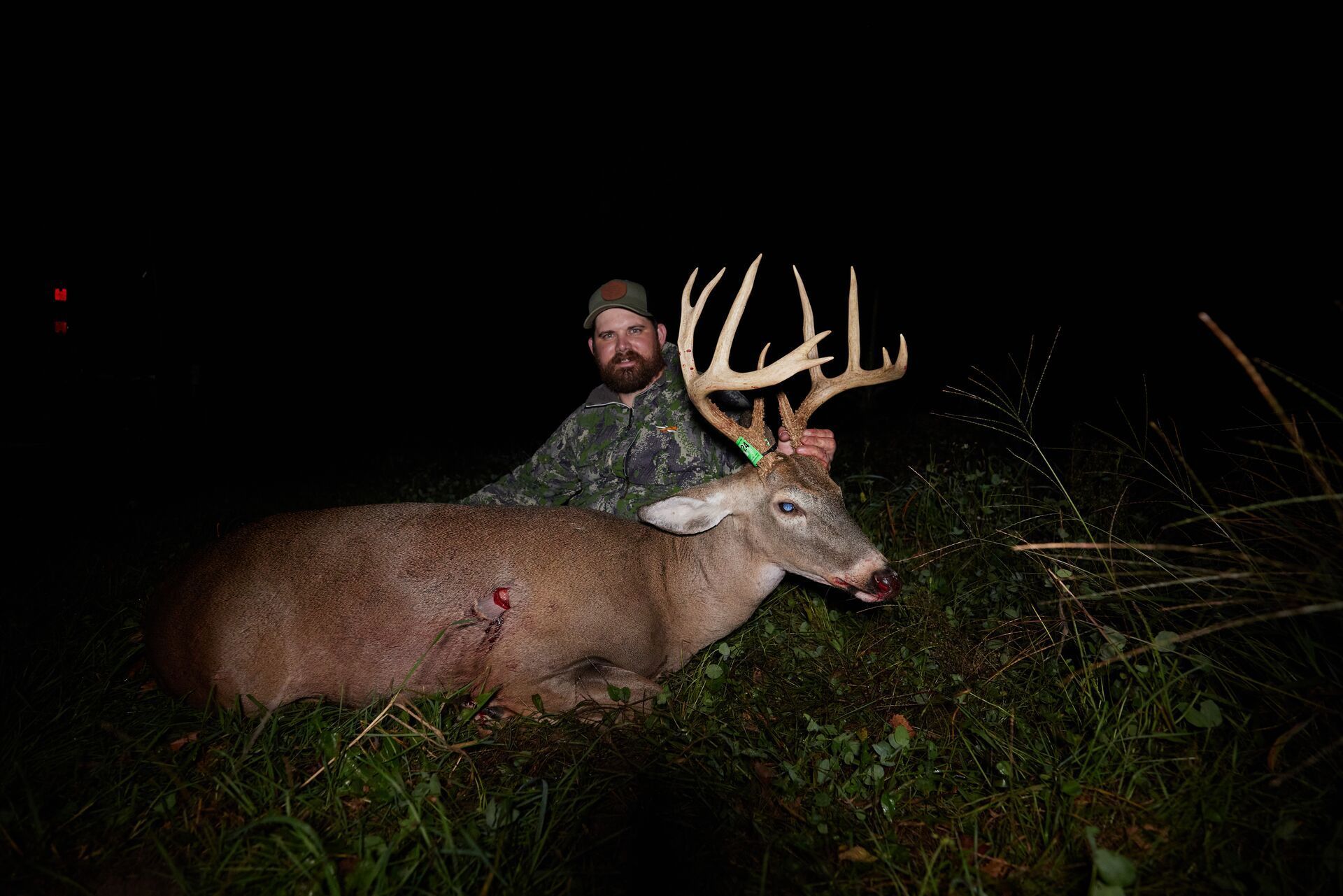 Hunter with a buck showing off large antlers, whitetail antler growth concept.