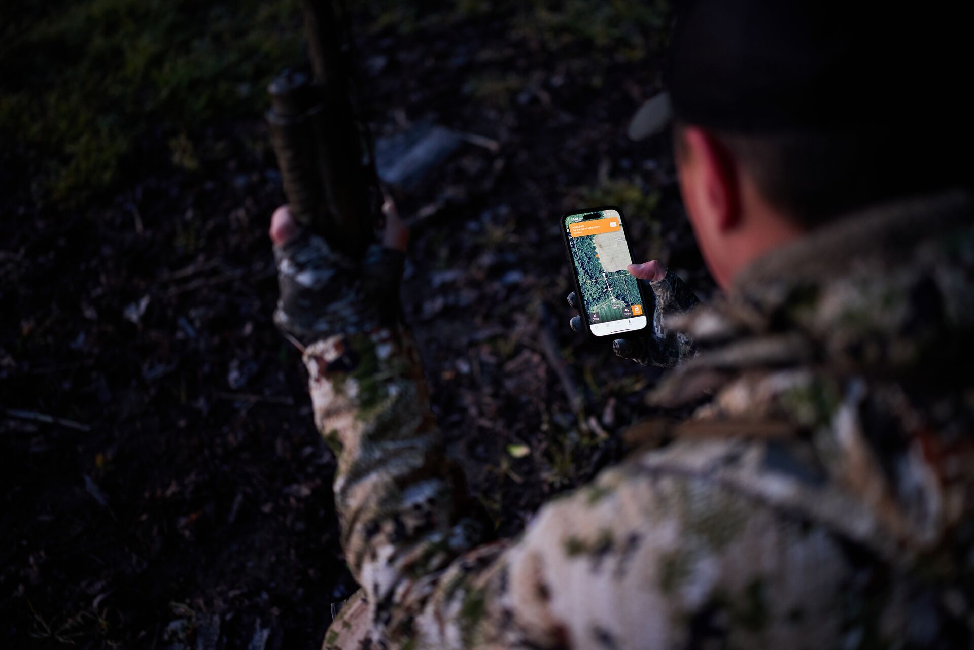 Hunter looks at phone with HuntWise maps on screen.
