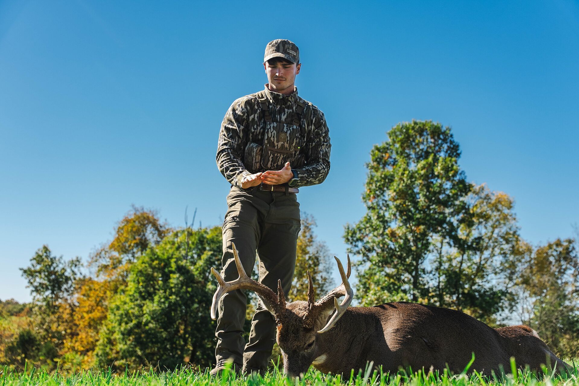 Hunter stands over buck deer on ground after hunt, PA deer hunt concept.