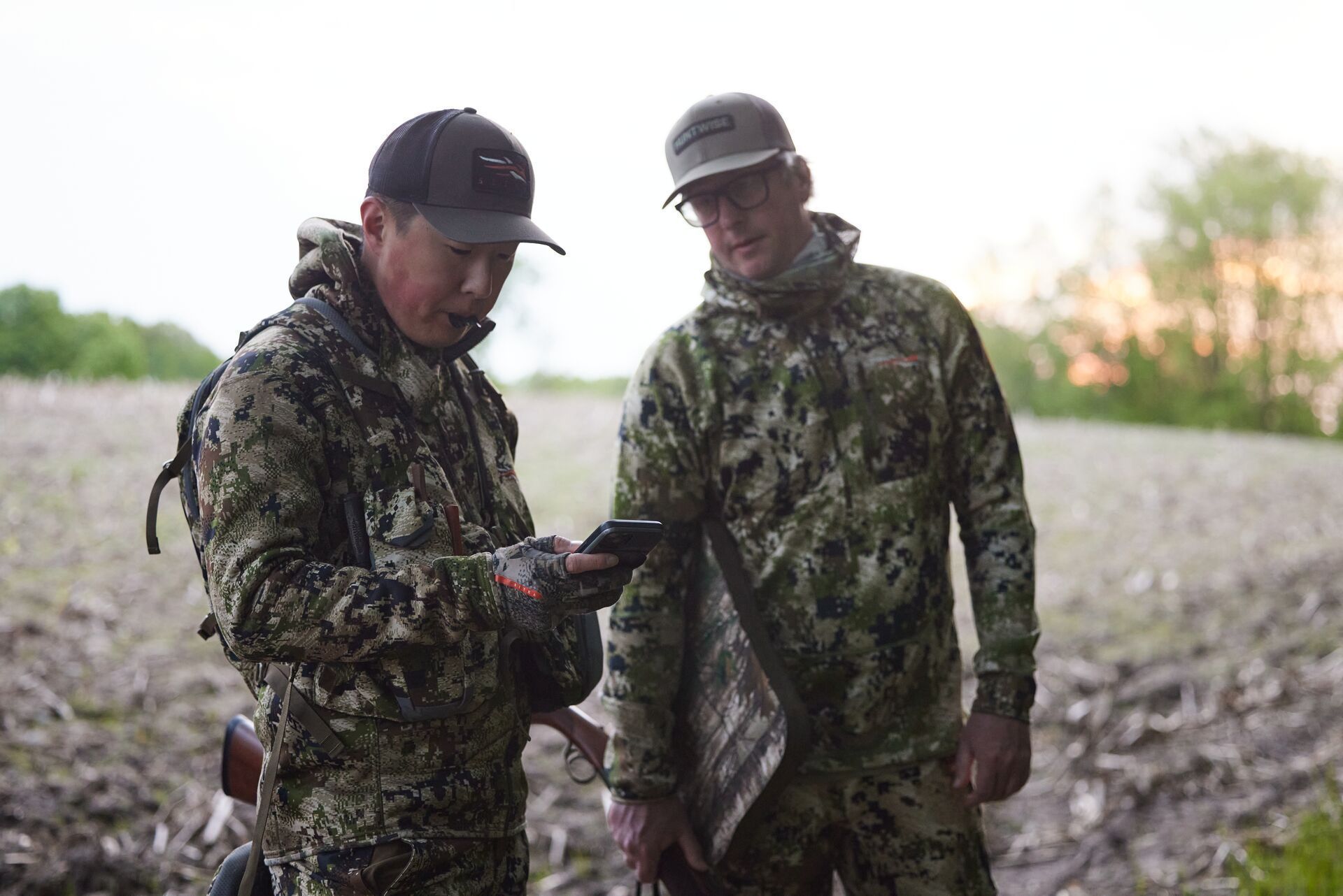 Two hunters using a phone with HuntWise to hunt turkeys.