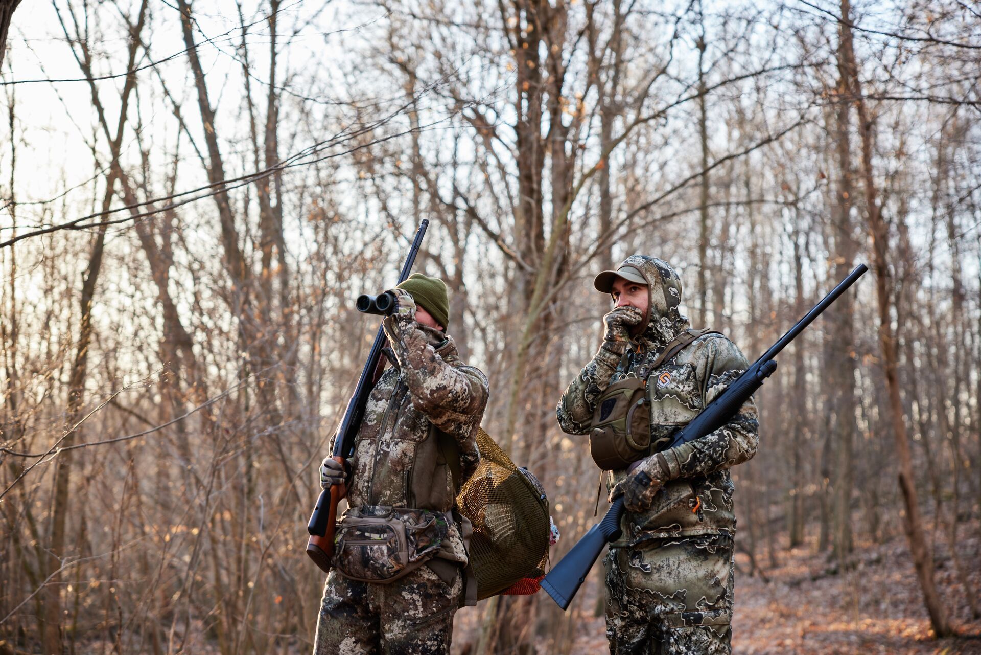 Two turkey hunters with shotguns in the woods, best states for turkey hunting concept.