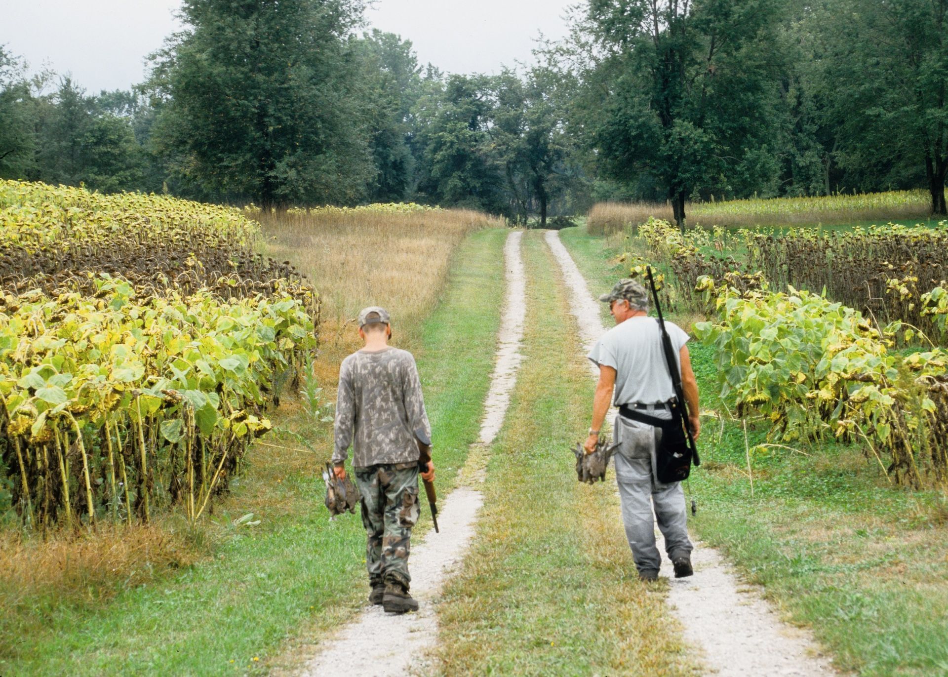 Two hunters walking carrying doves after hunt.