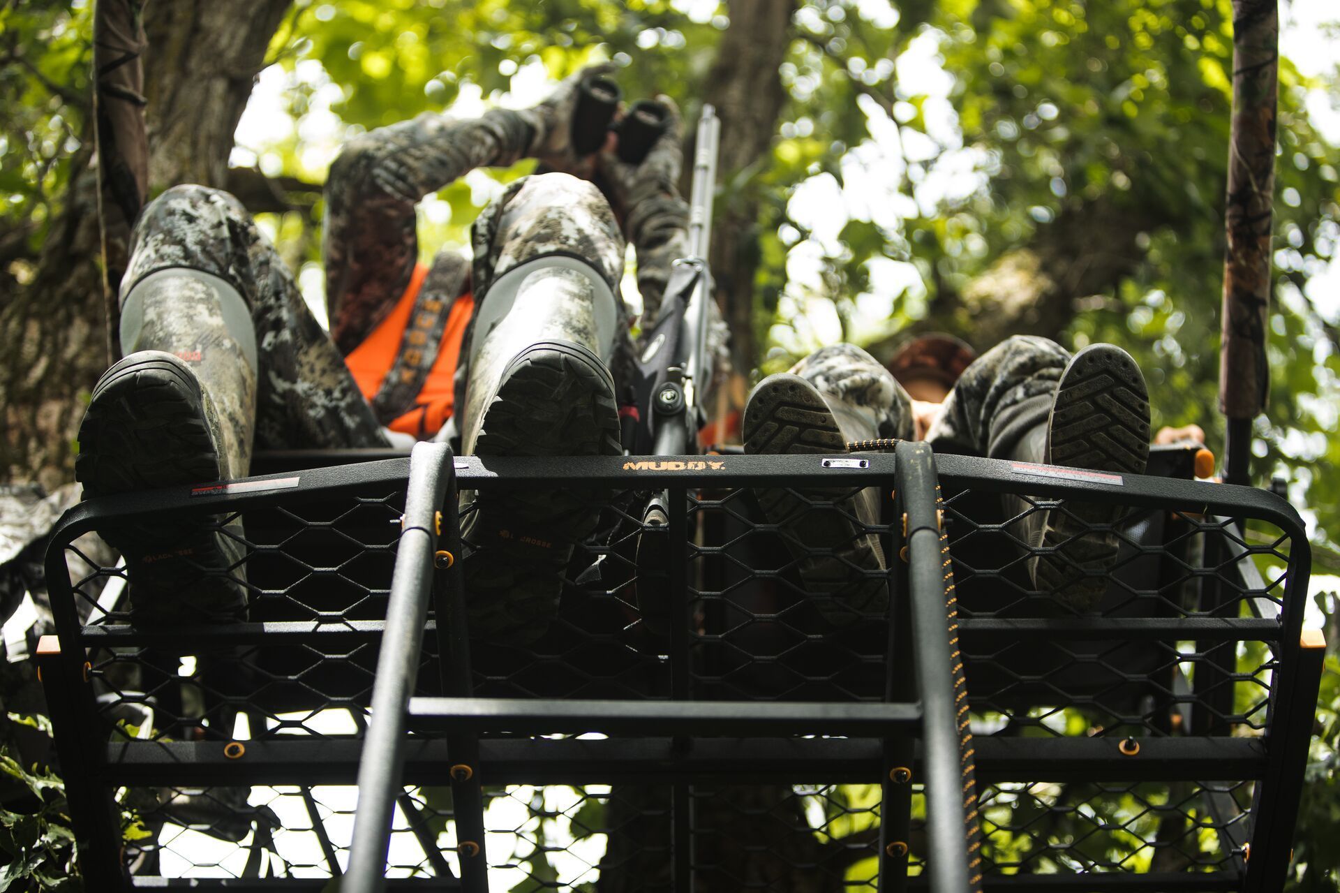 Two hunters sit in a tree stand, black-tailed deer hunting concept.