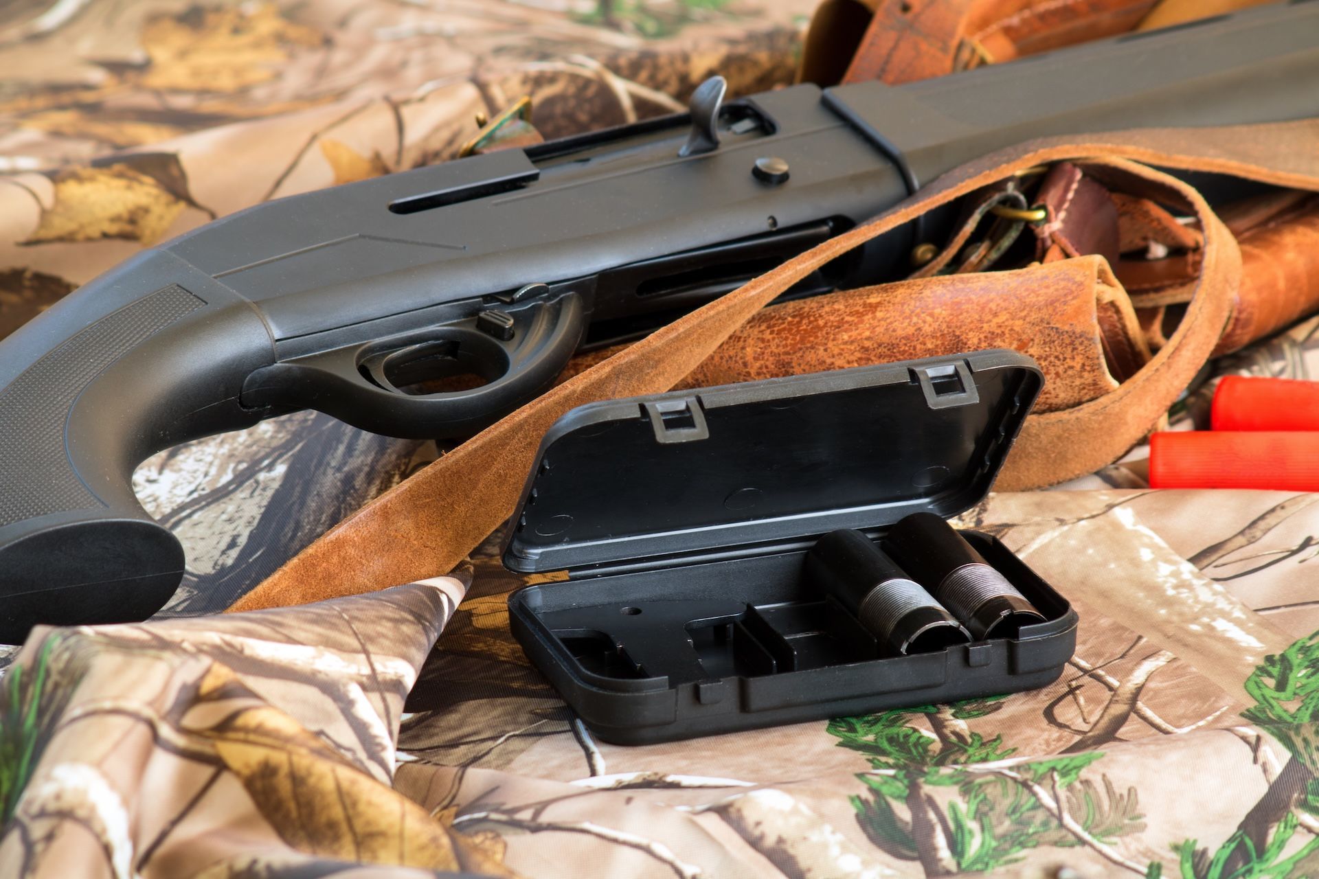 Shotgun next to a box with shotgun chokes.