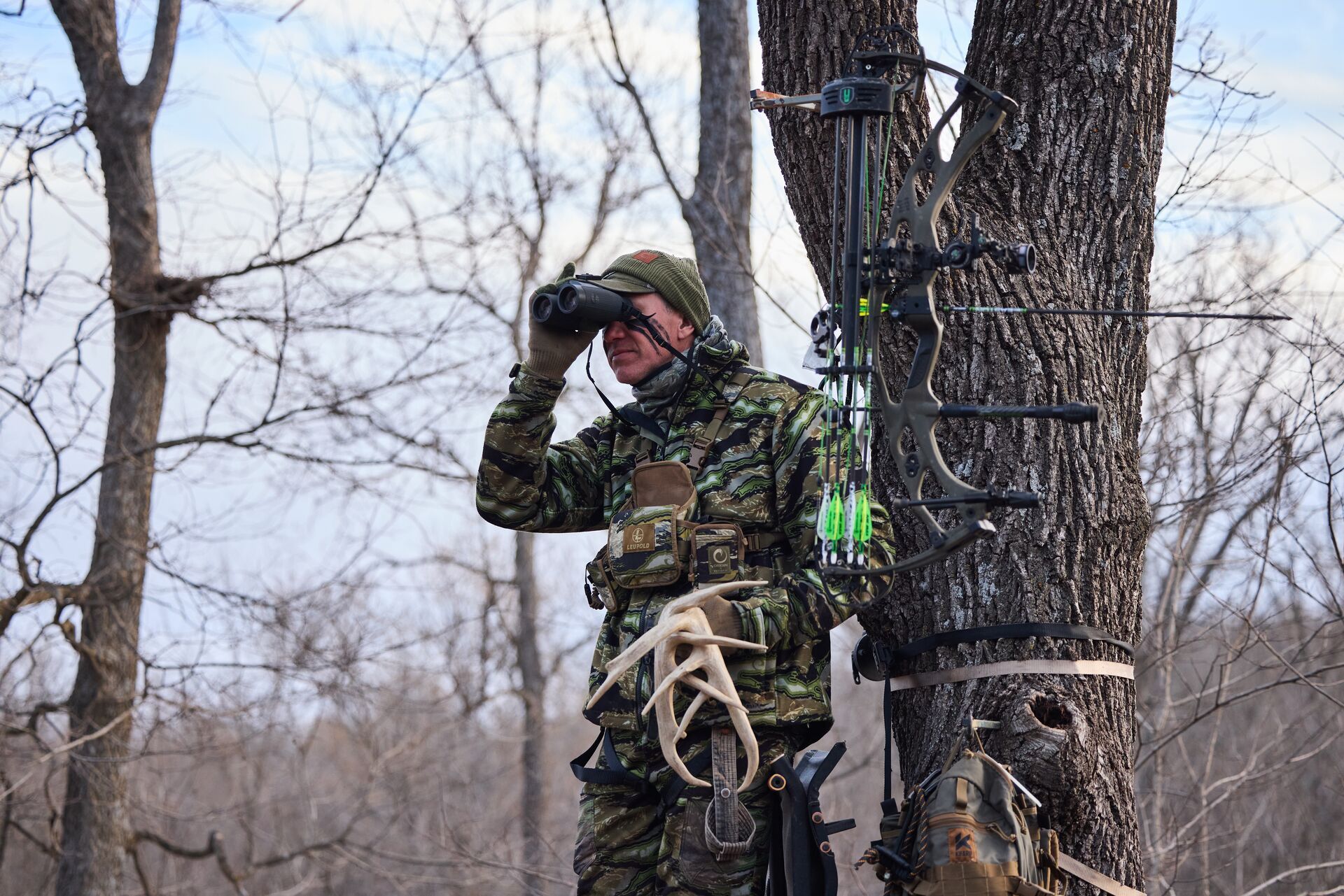 John Dudley geared up with camo, bow, and binoculars, gear for deer hunting concept.