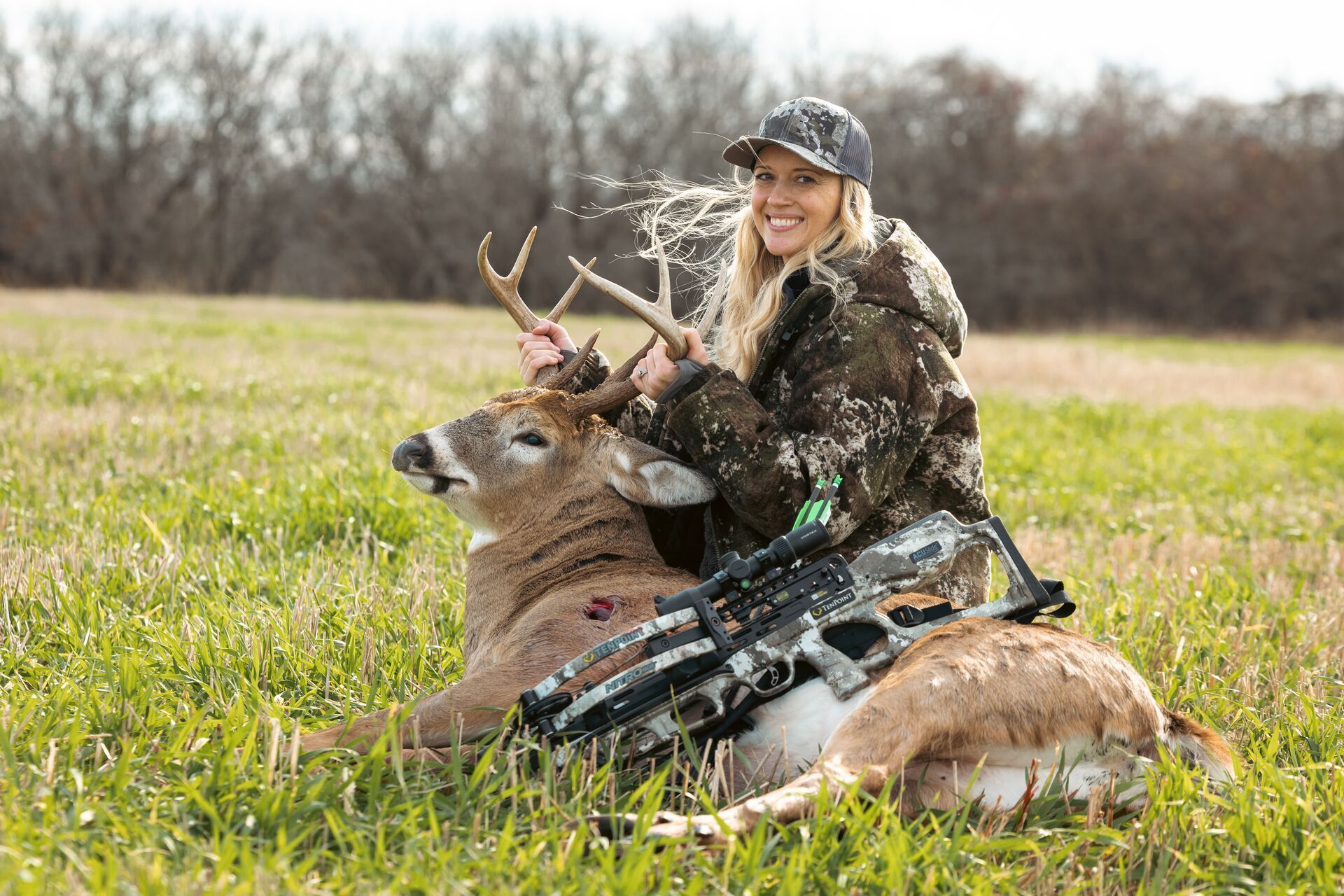A female hunter shows off a big whitetail buck after a hunt, Illinois deer season concept.