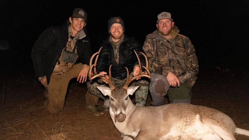 Three hunters with a buck deer after hunt, best times to hunt whitetail concept. 