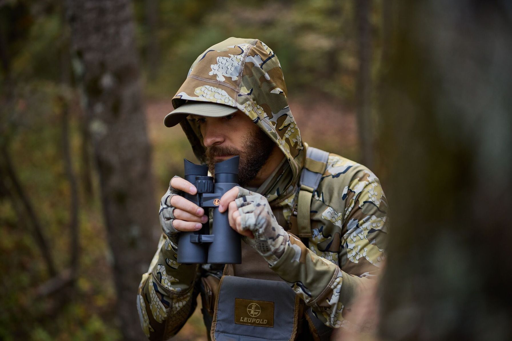 Hunter with binoculars in the woods, best optics for mule deer hunting concept.