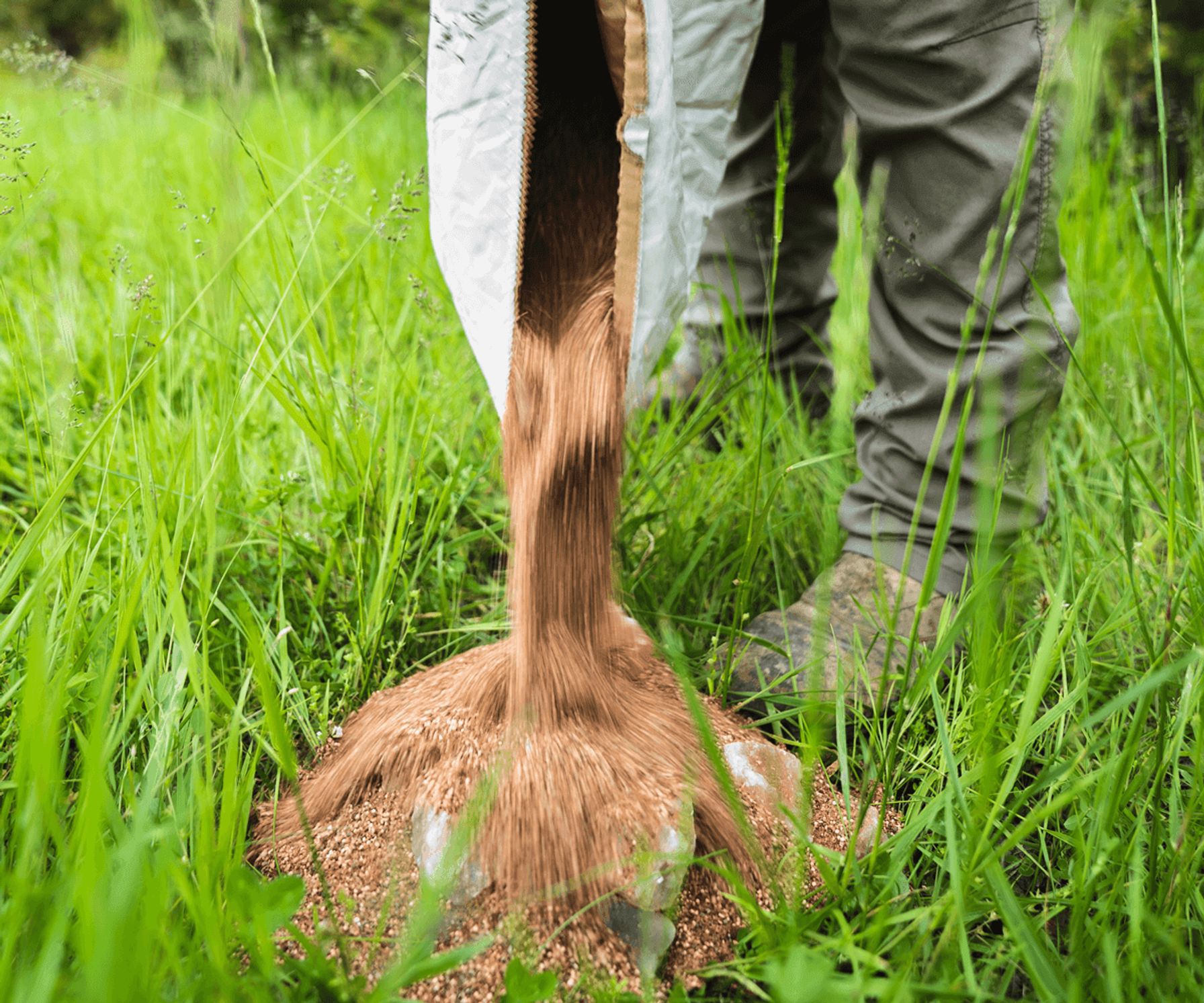 Close-up of hunter pouring minerals on the ground, how to make mineral sites for deer concept.