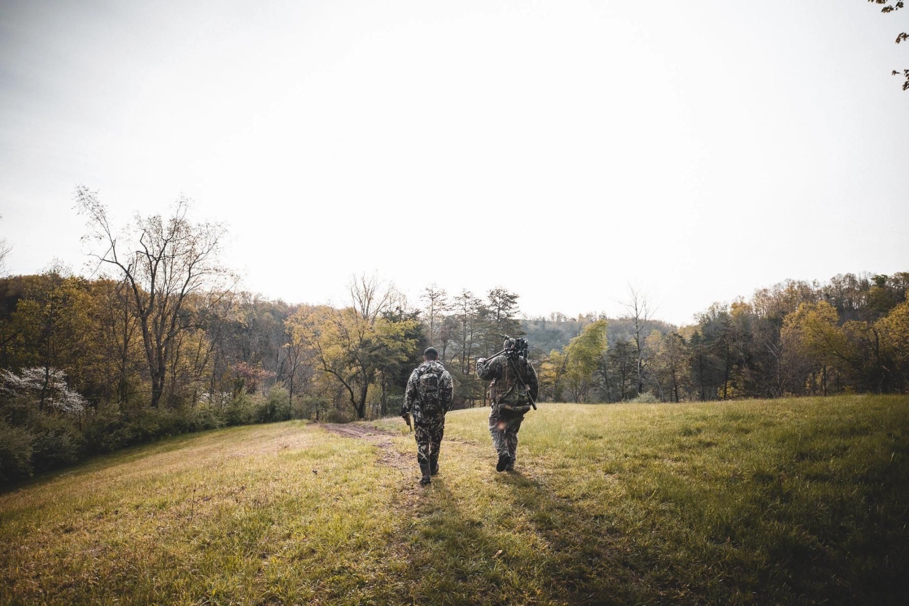 Two hunters with hunting gear walking across a field, axis deer hunting Texas concept.