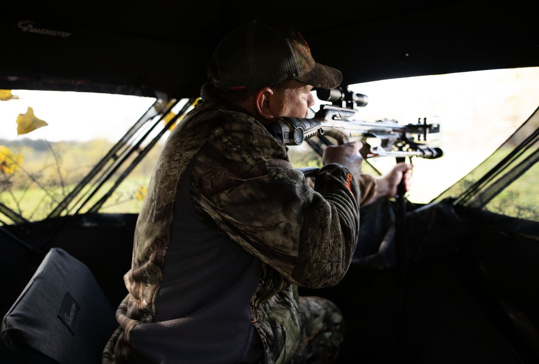 A hunter takes aim while in a ground blind.