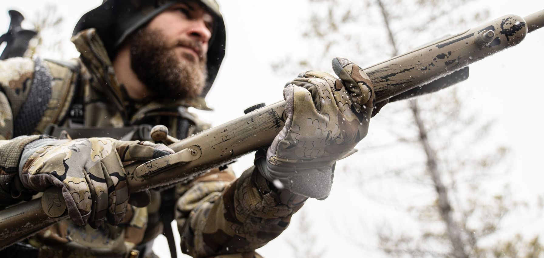 Hunter in camo with rifle for hunt.