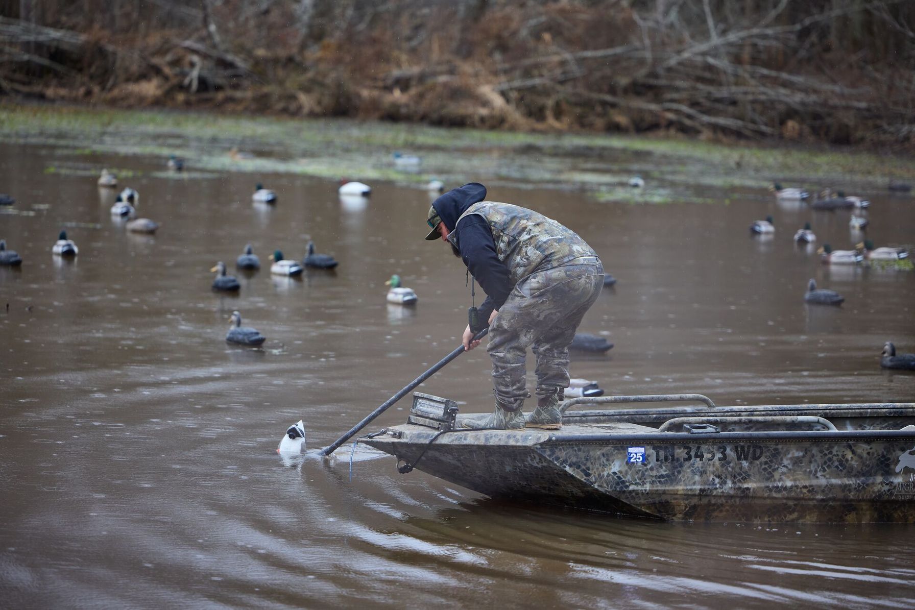 A waterfowl hunter in a boat places duck decoys.