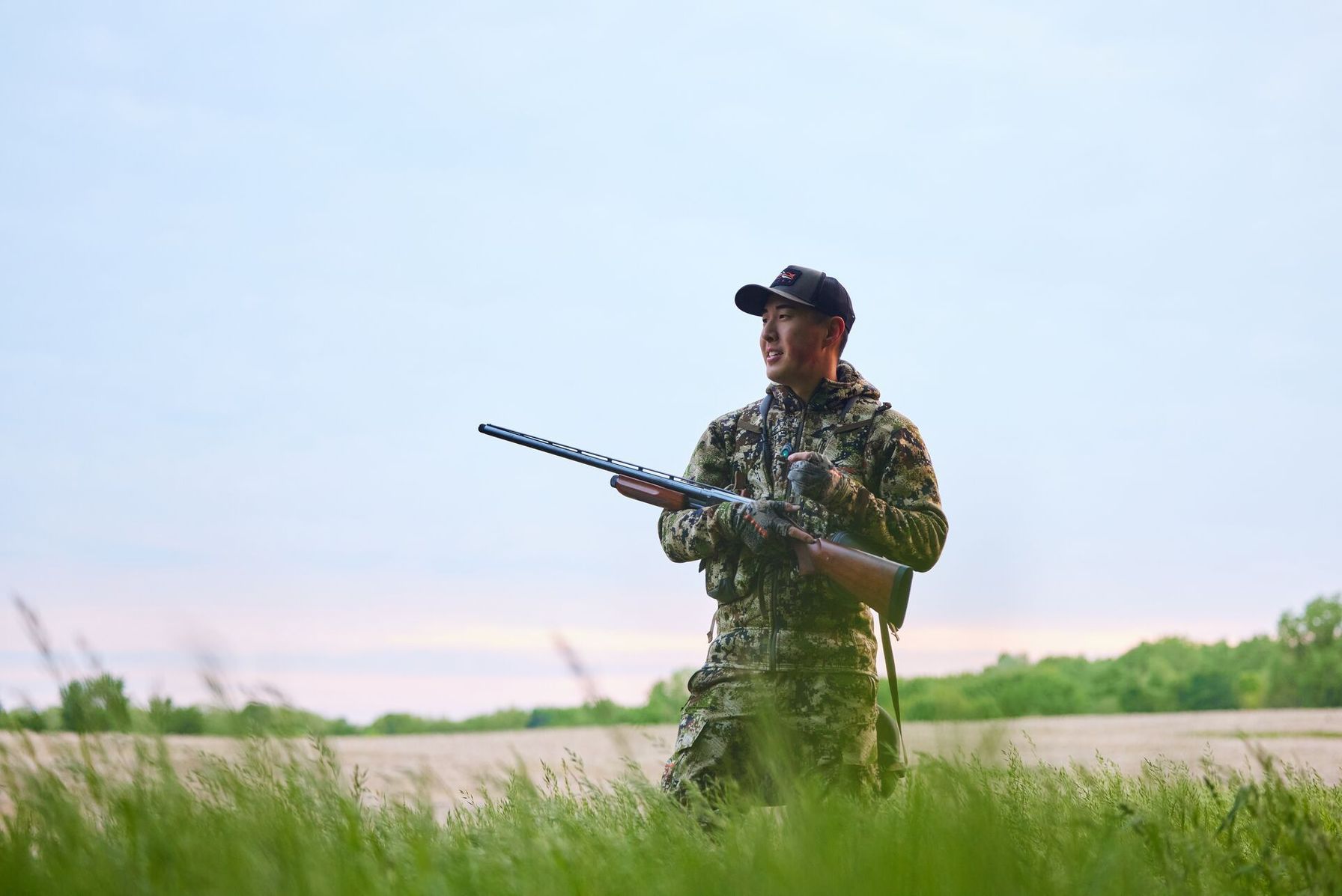 A hunter with a firearm in a field, hunting in Louisiana concept.