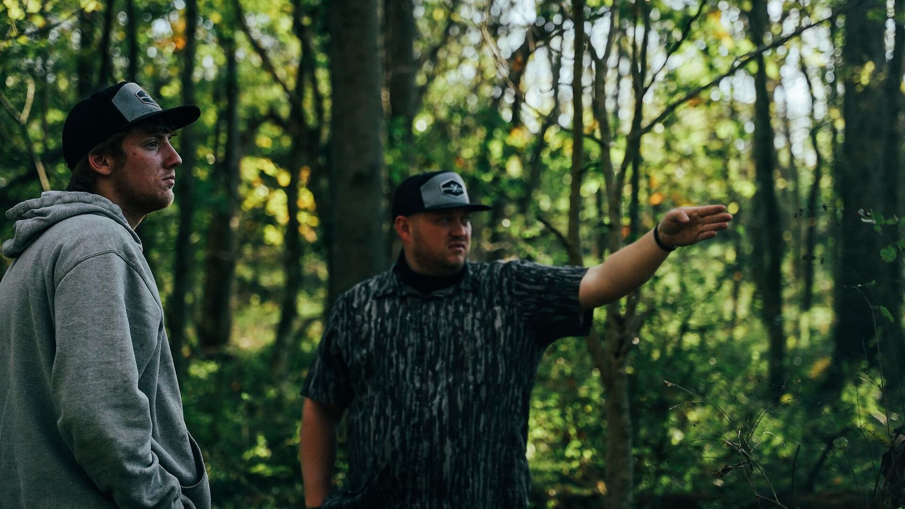 Two hunters talking and pointing in the woods, where can I hunt near me concept.