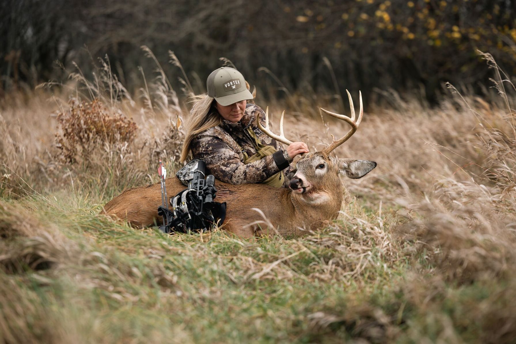 Female hunter with a deer and bow on the ground after hunt, Utah deer season concept.