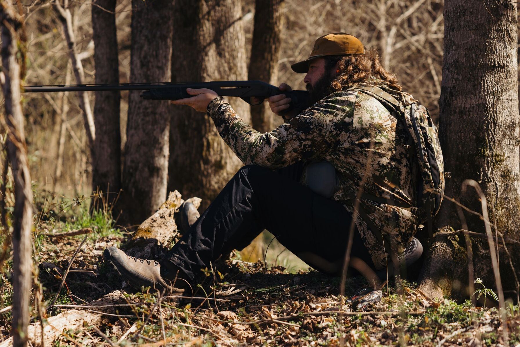 Ben Cole of RootedTV aims a shotgun in the woods, turkey patterning concept.