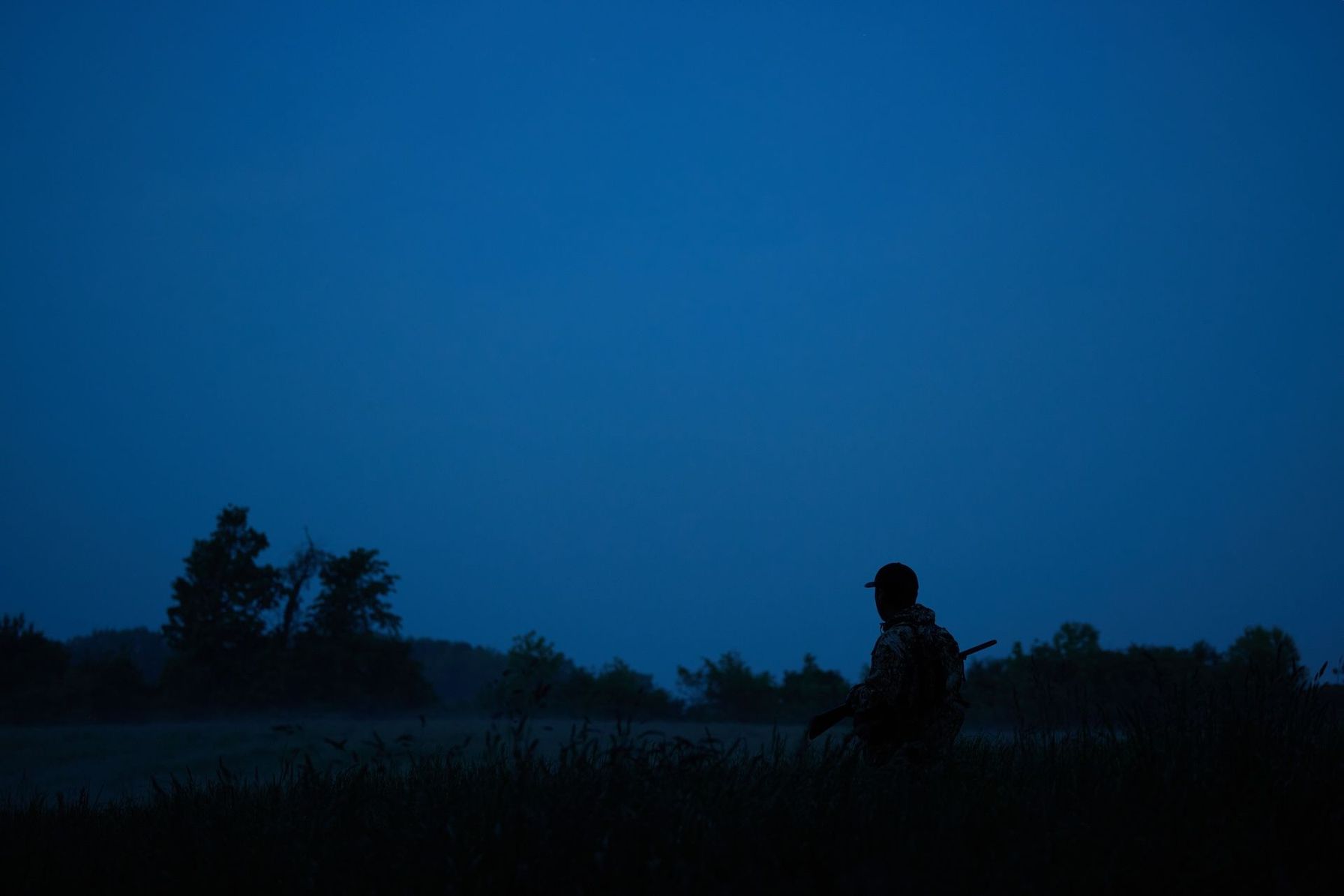 A hunter looks across a field in the dark, night hunting concept.