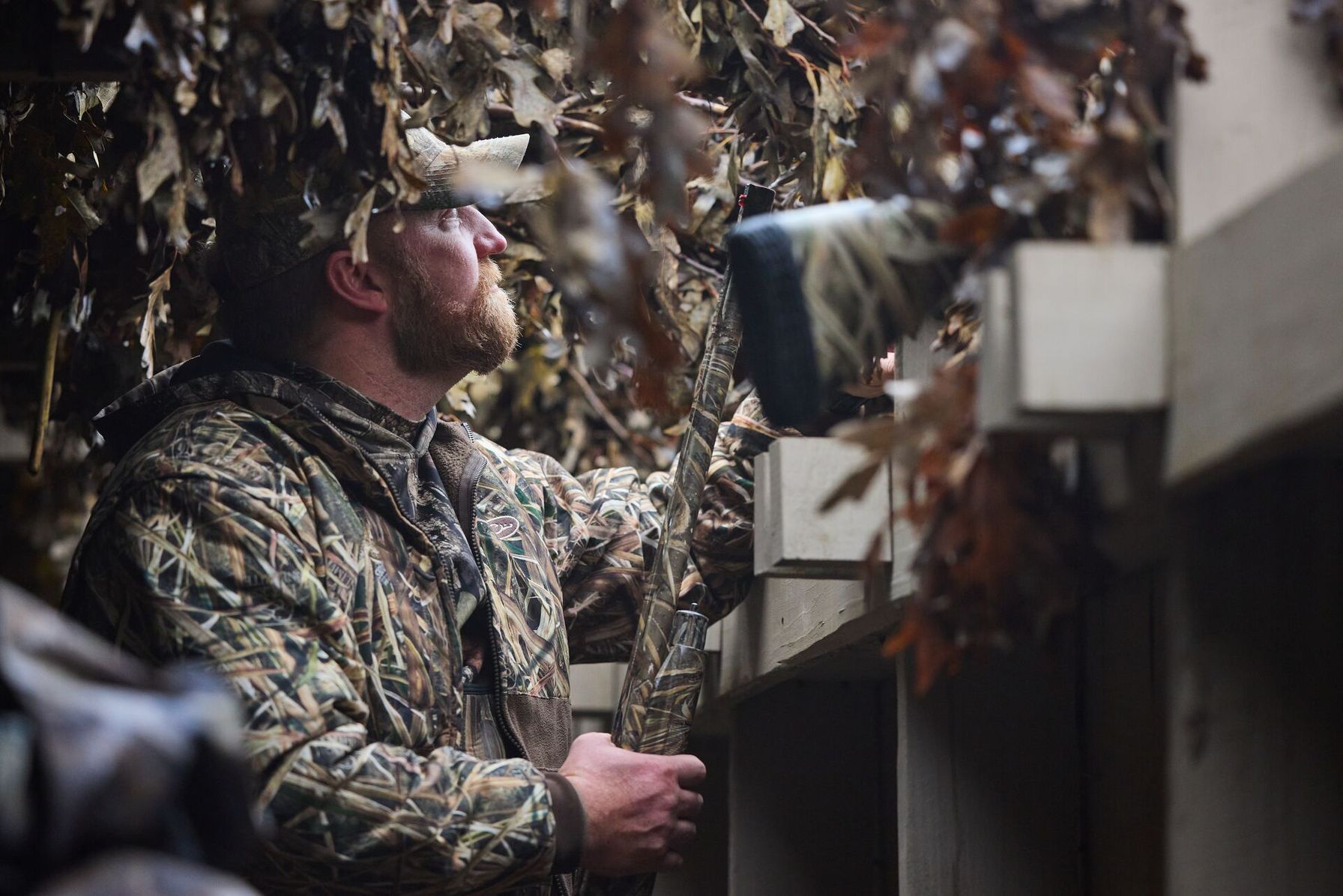 Hunter looking up and out of duck blind for hunt.
