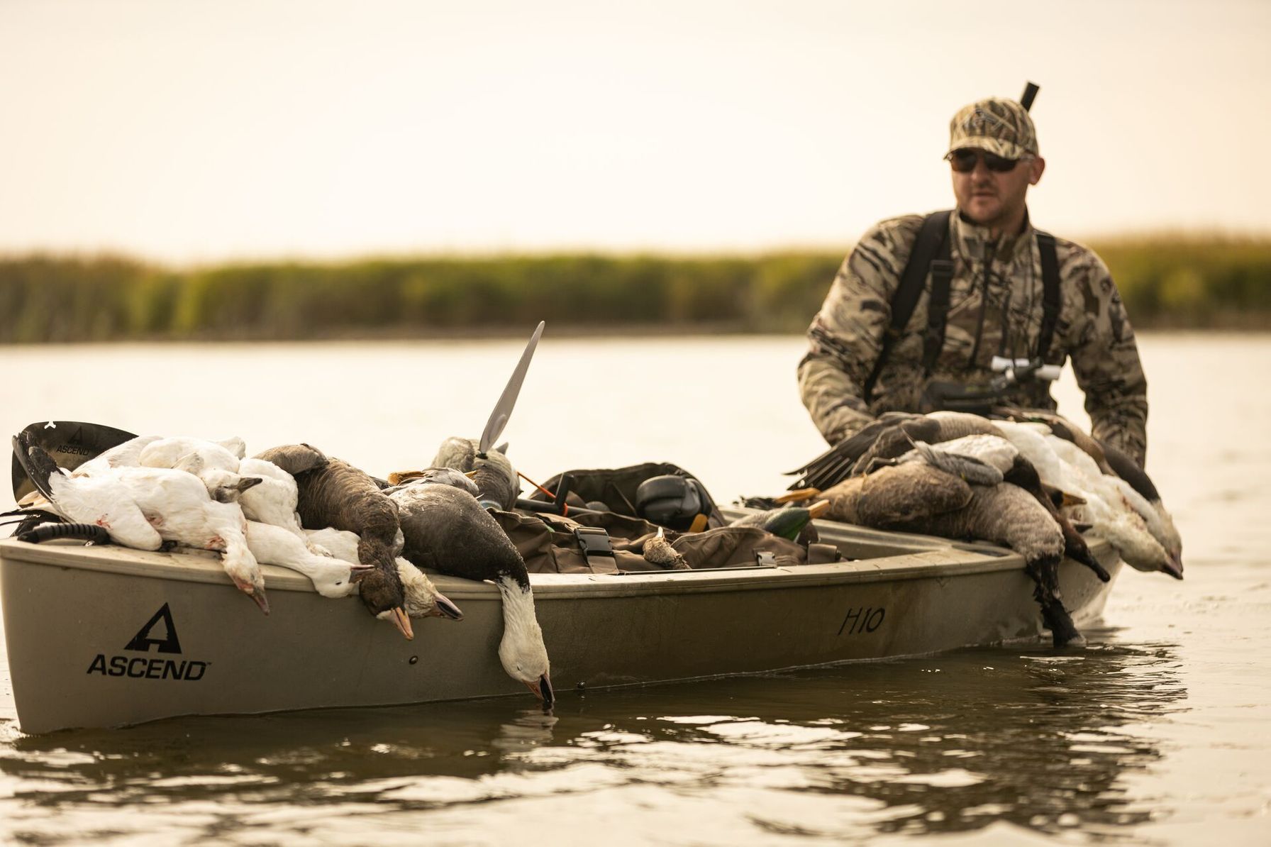 A hunter in a small fishing boat full of geese after a hunt, Nevada hunting seasons concept.