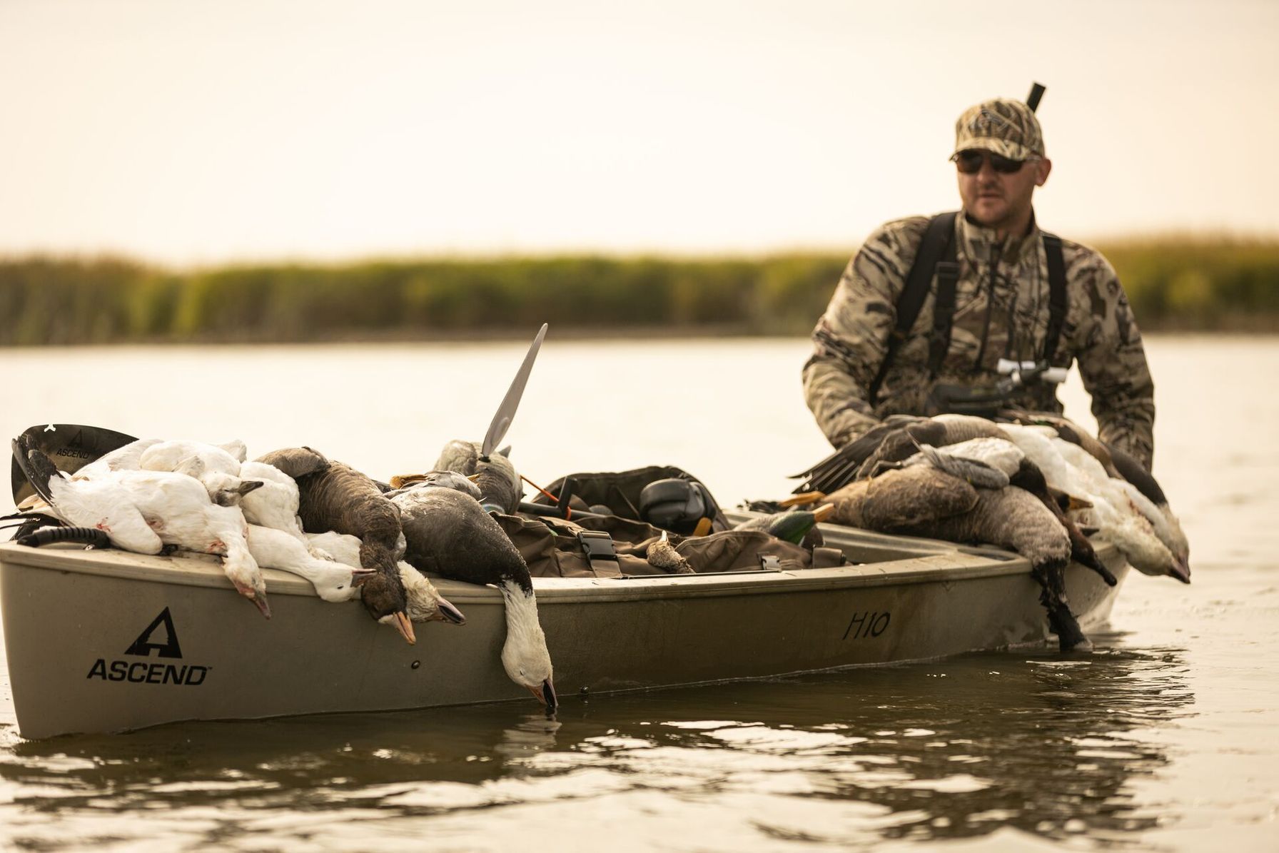 A hunter in a small fishing boat full of geese after a hunt, Nevada hunting seasons concept.