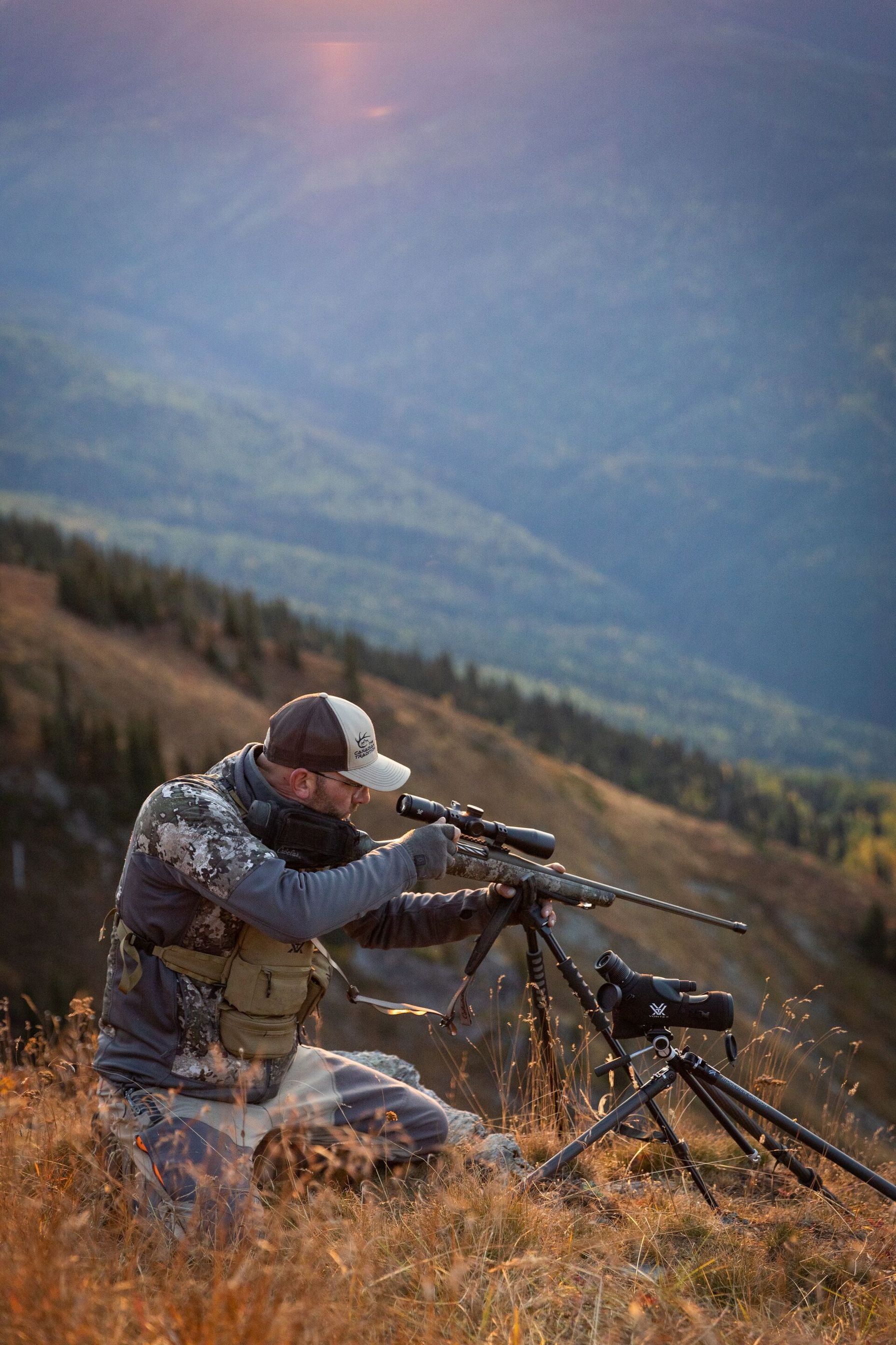 Hunter on a hill aims a rifle, plan guided mule deer hunt concept.