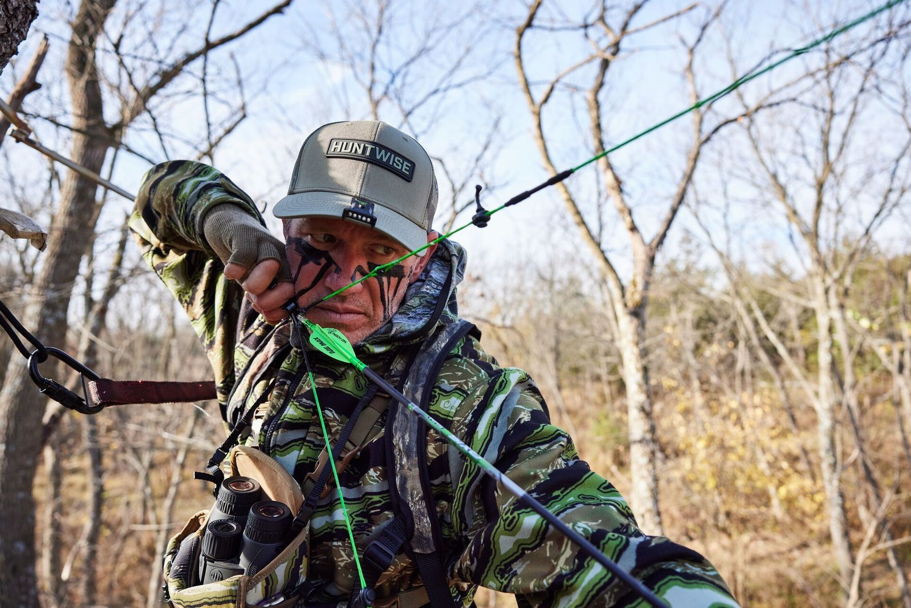 Hunter John Dudley draws a bow in the field, archery strength training concept.