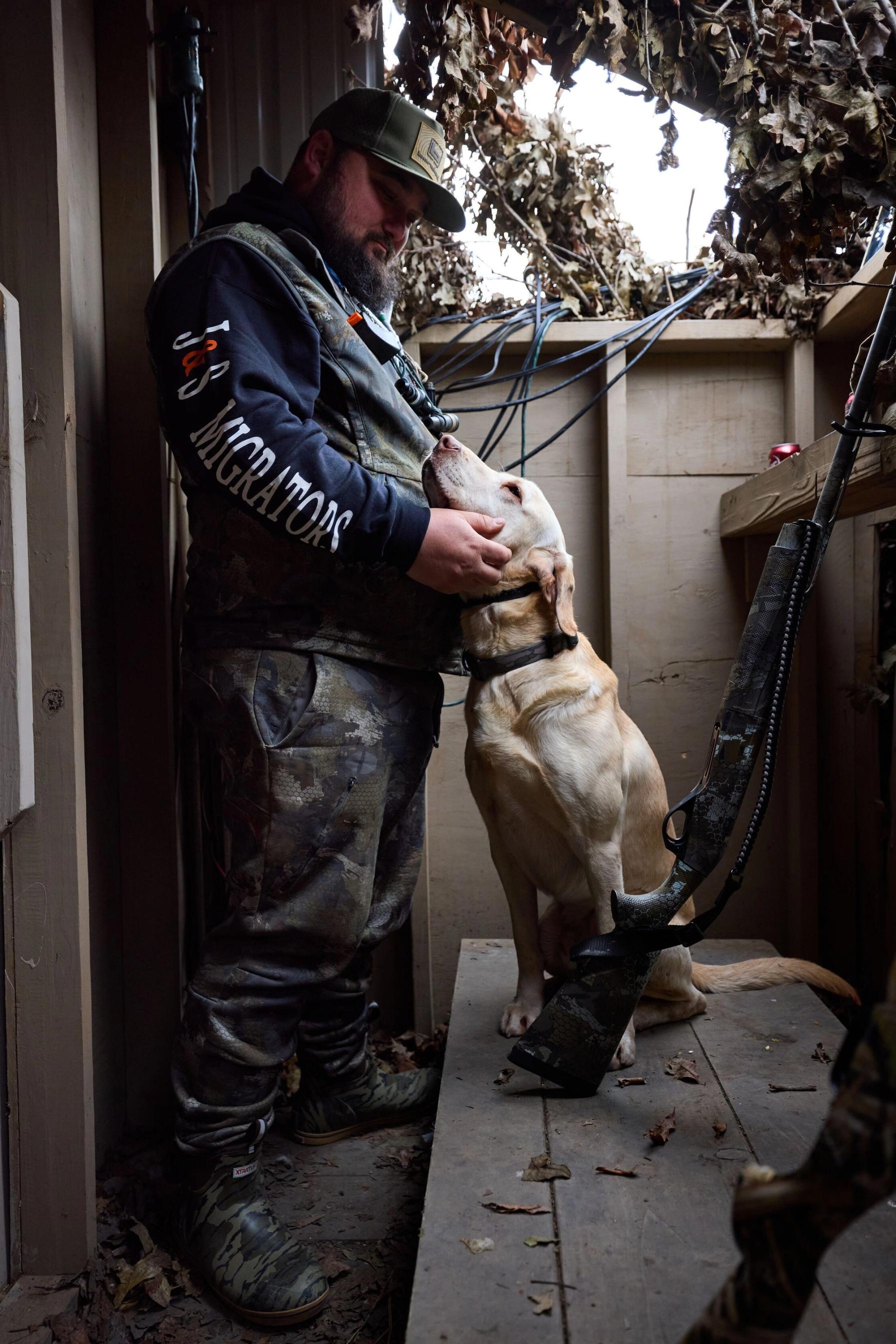 Hunter with dog and shotgun in duck blind, shotgun for hunting concept.