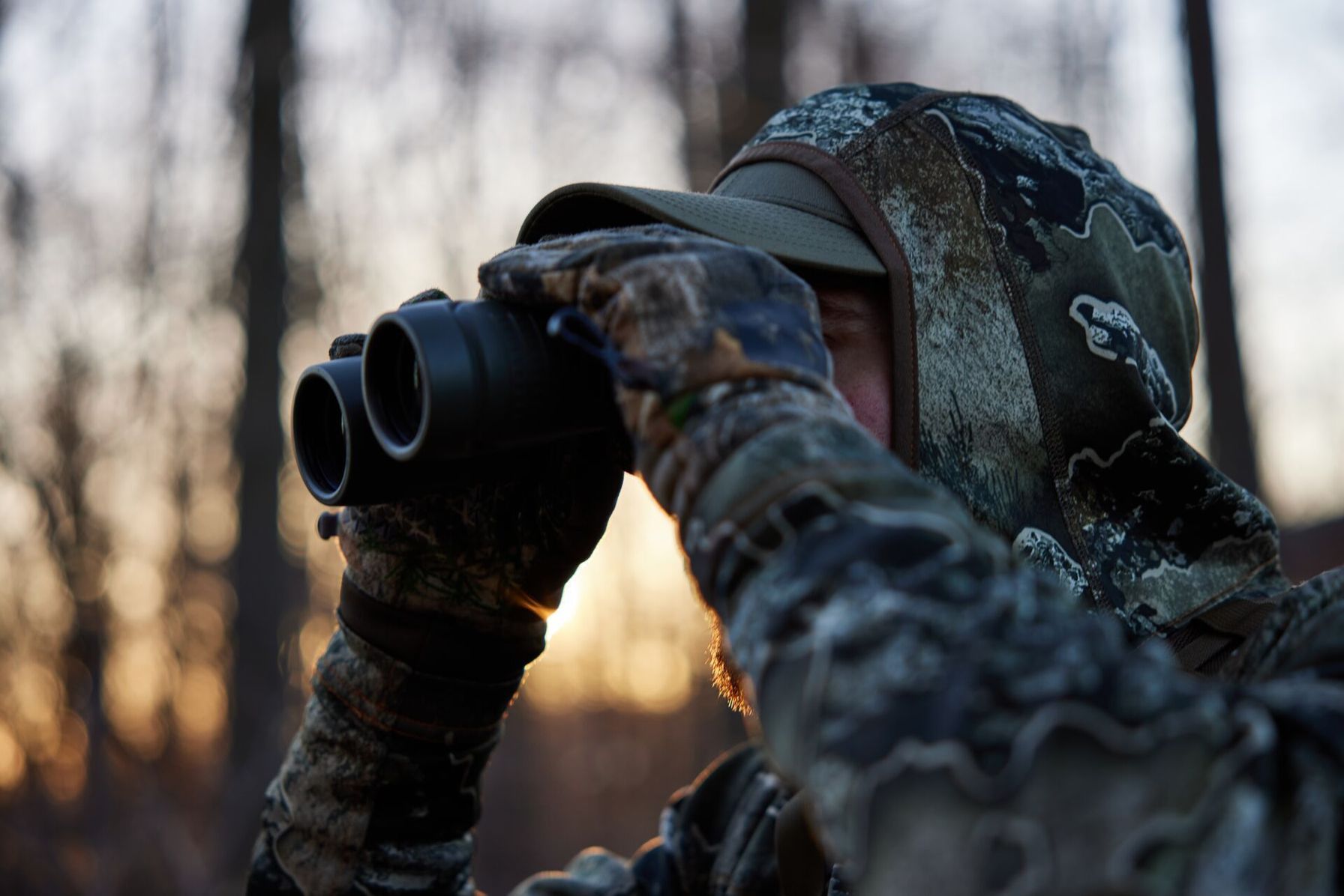 A hunter uses binoculars, glassing and stalking whitetail concept.