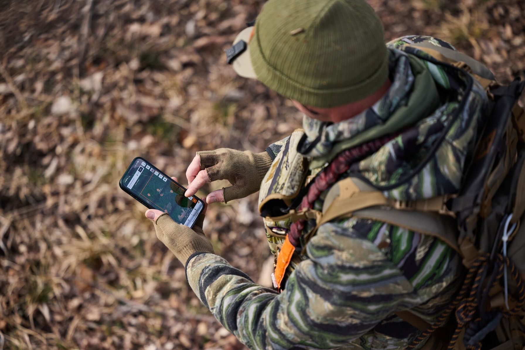 Hunter using the HuntWise app to review pins, find public deer hunting land concept.