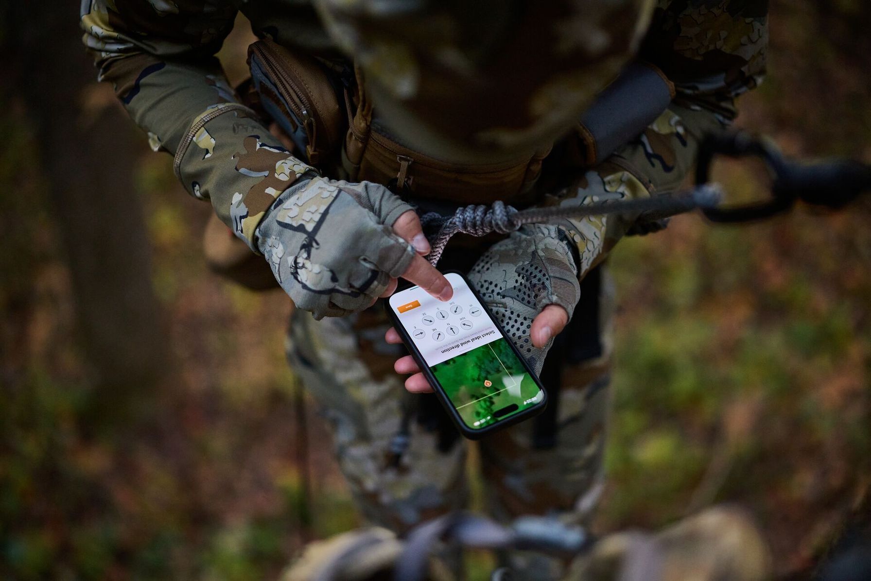 Hunter using HuntWise app on phone while in tree saddle.