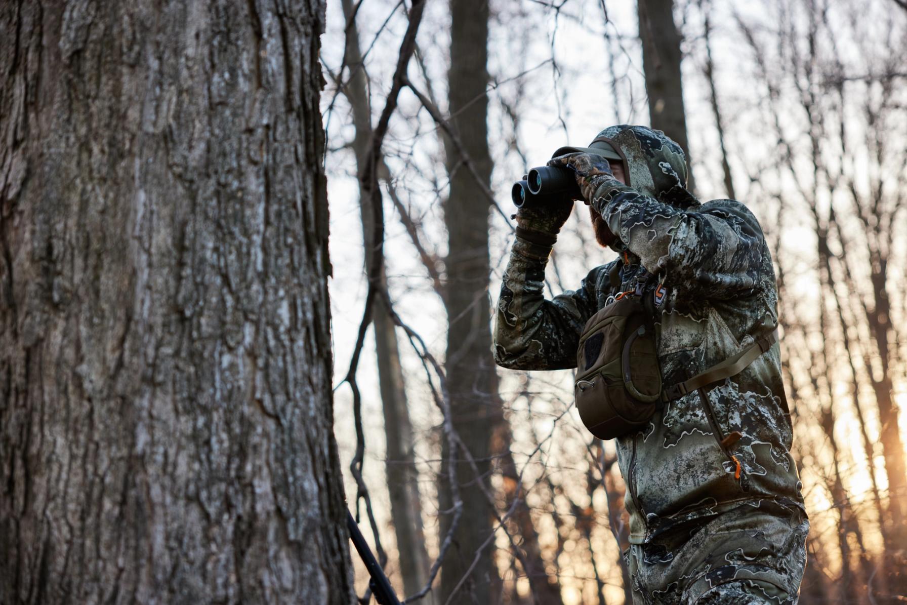 A hunter in camo using binoculars, Indiana turkey season concept.