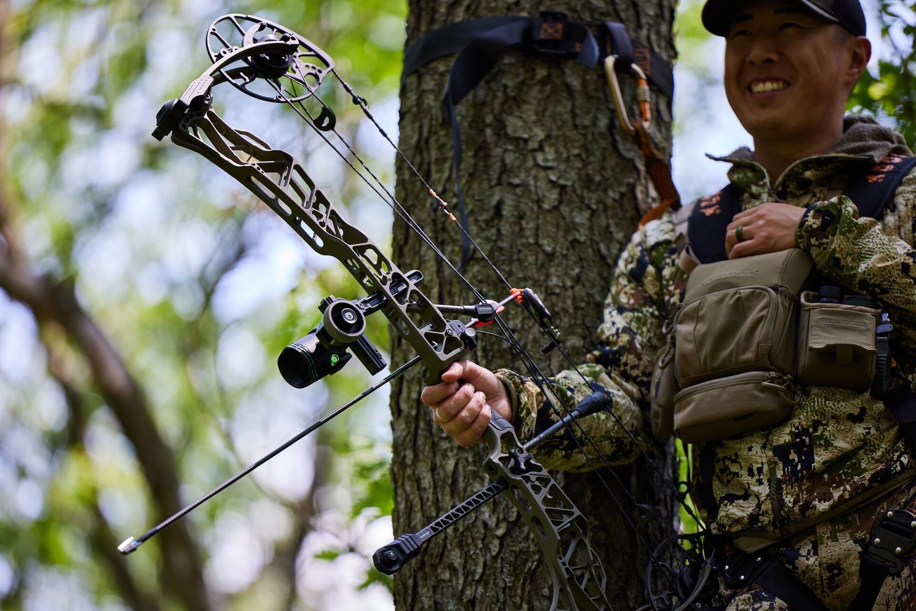A smiling hunter in camo with a bow, deer hunting season NY concept.