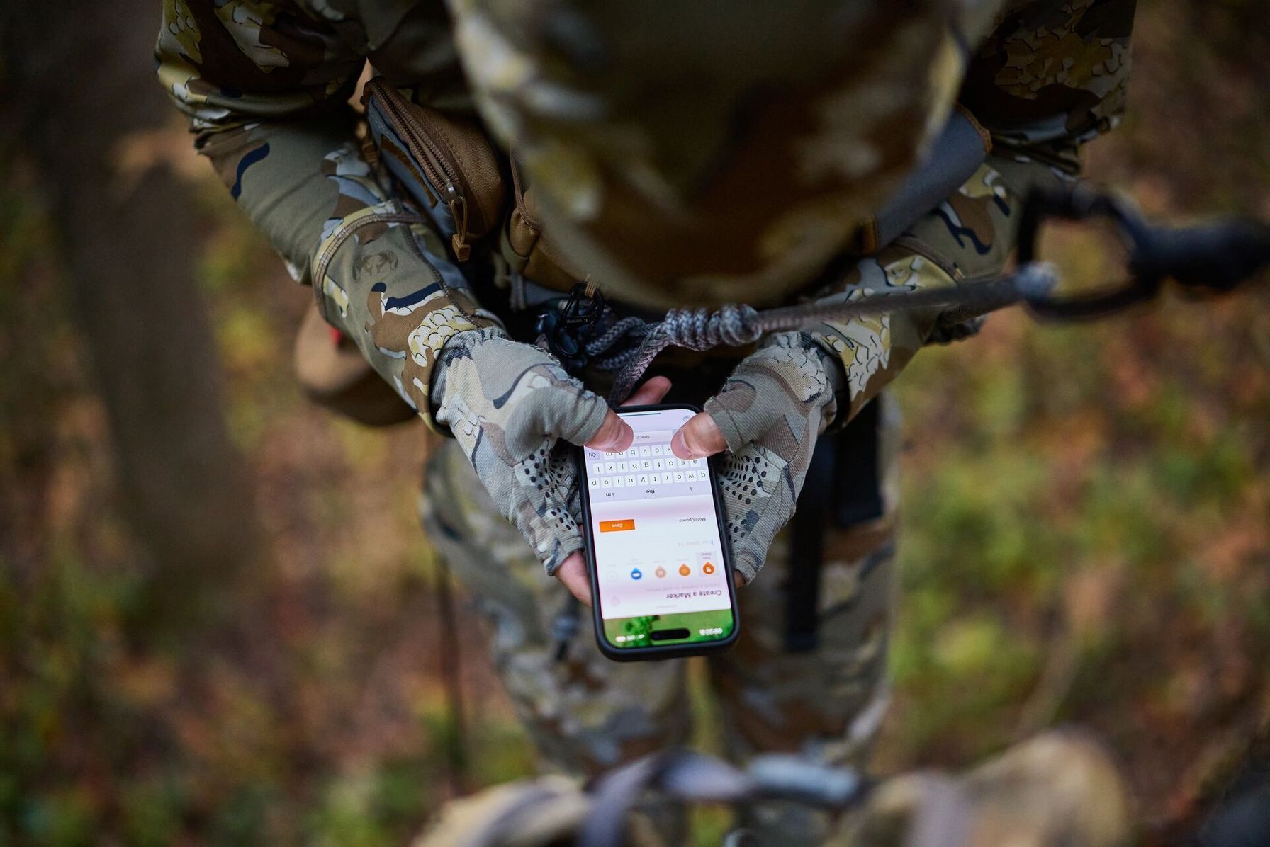 Hunter in tree saddle uses HuntWise on phone, how to see property lines while hunting concept. 