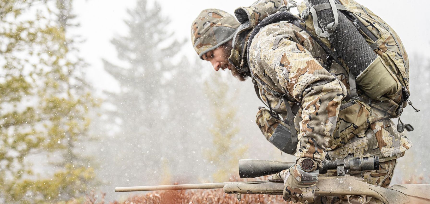 Hunter in camo with rifle walks in light snow, December hunting tips concept.