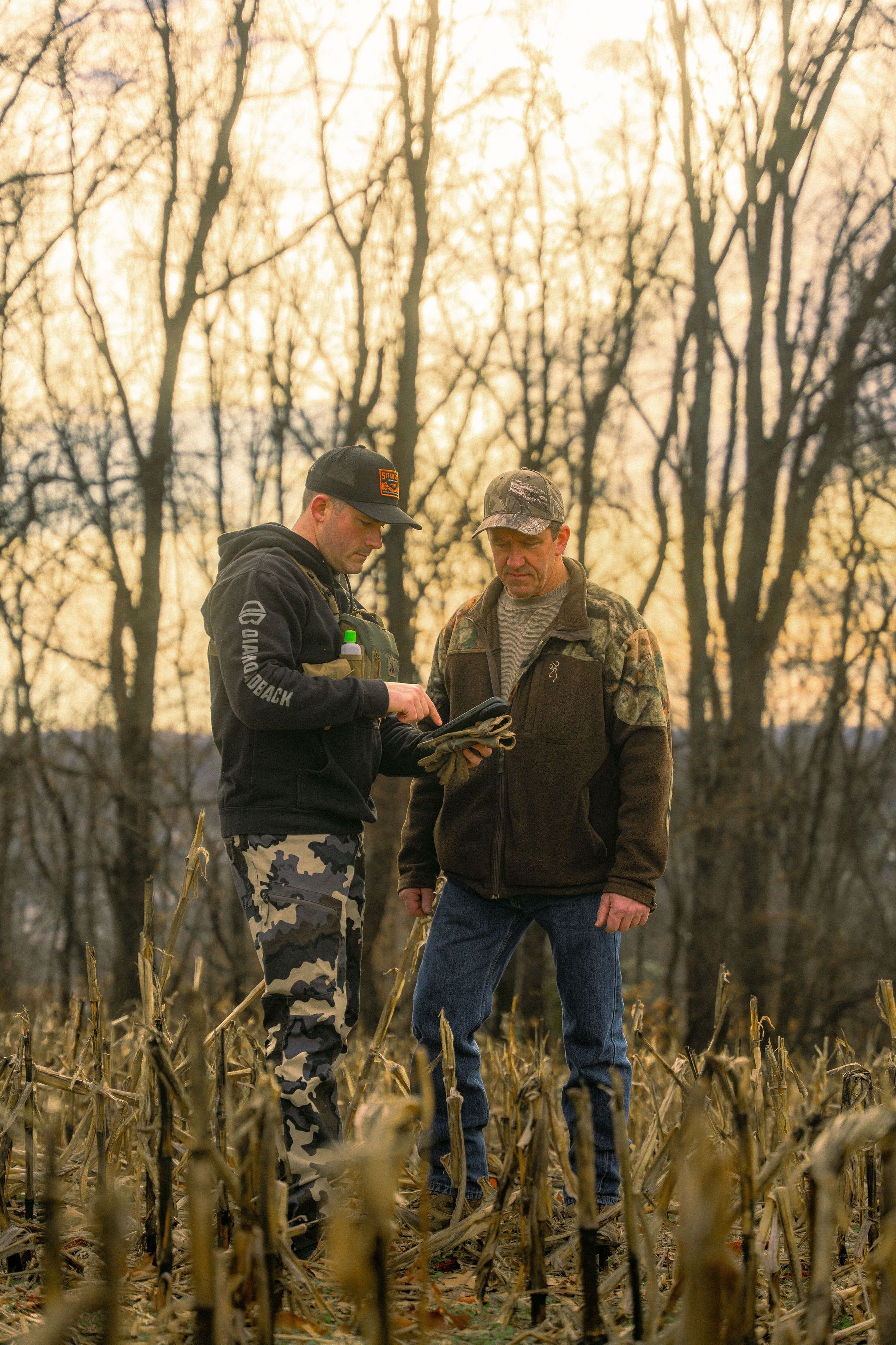 Two men in field looking at phone, coyote tracking concept.